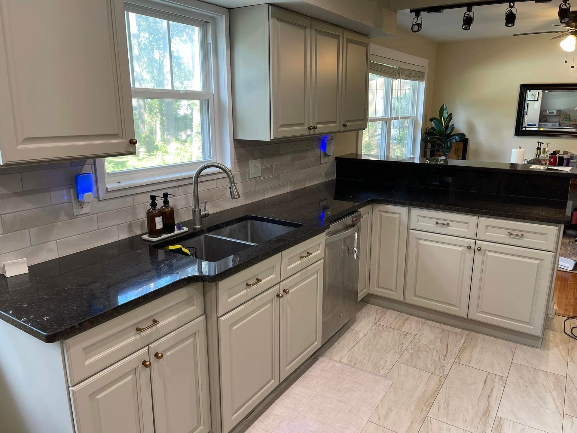 Kitchen with light gray cabinets, black countertops, stainless steel sink and dishwasher.