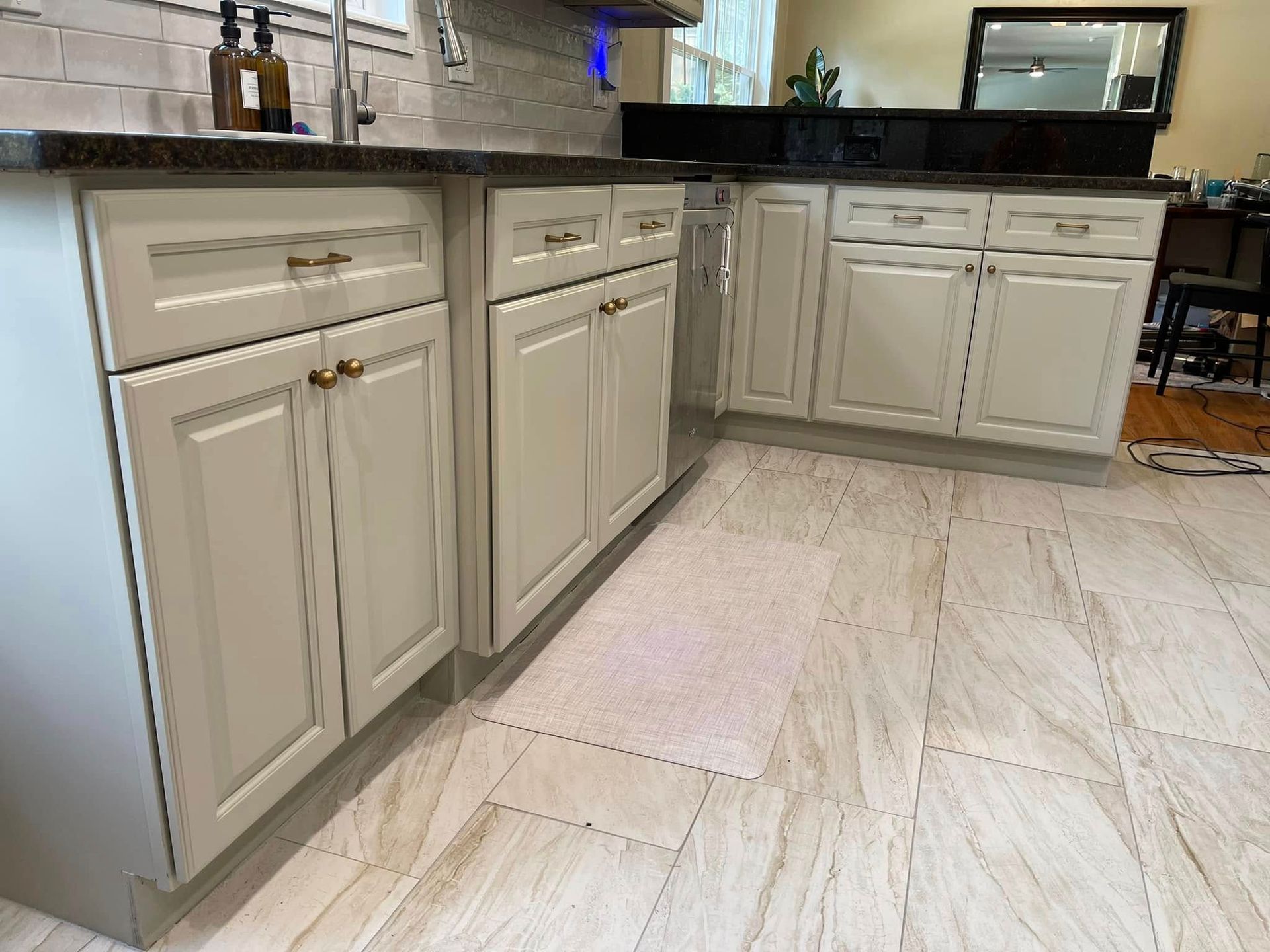 Cream kitchen cabinets with dark countertops and tan tile floor.