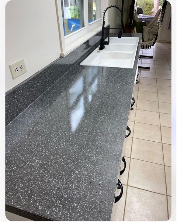 Dark gray speckled countertop with a double sink, black faucet, and cabinets.
