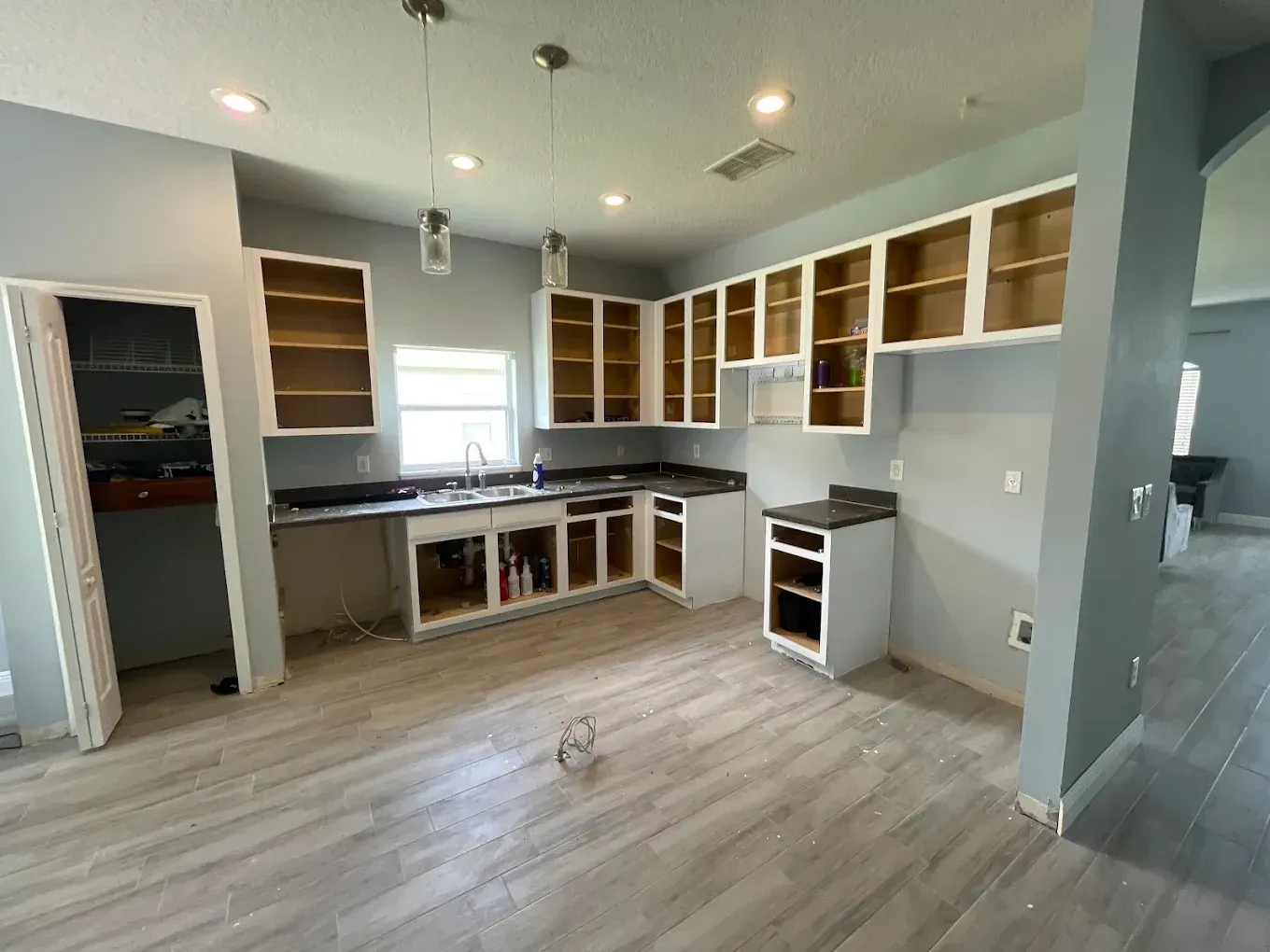 Kitchen renovation with gray walls, white cabinets, black countertops, and new flooring.