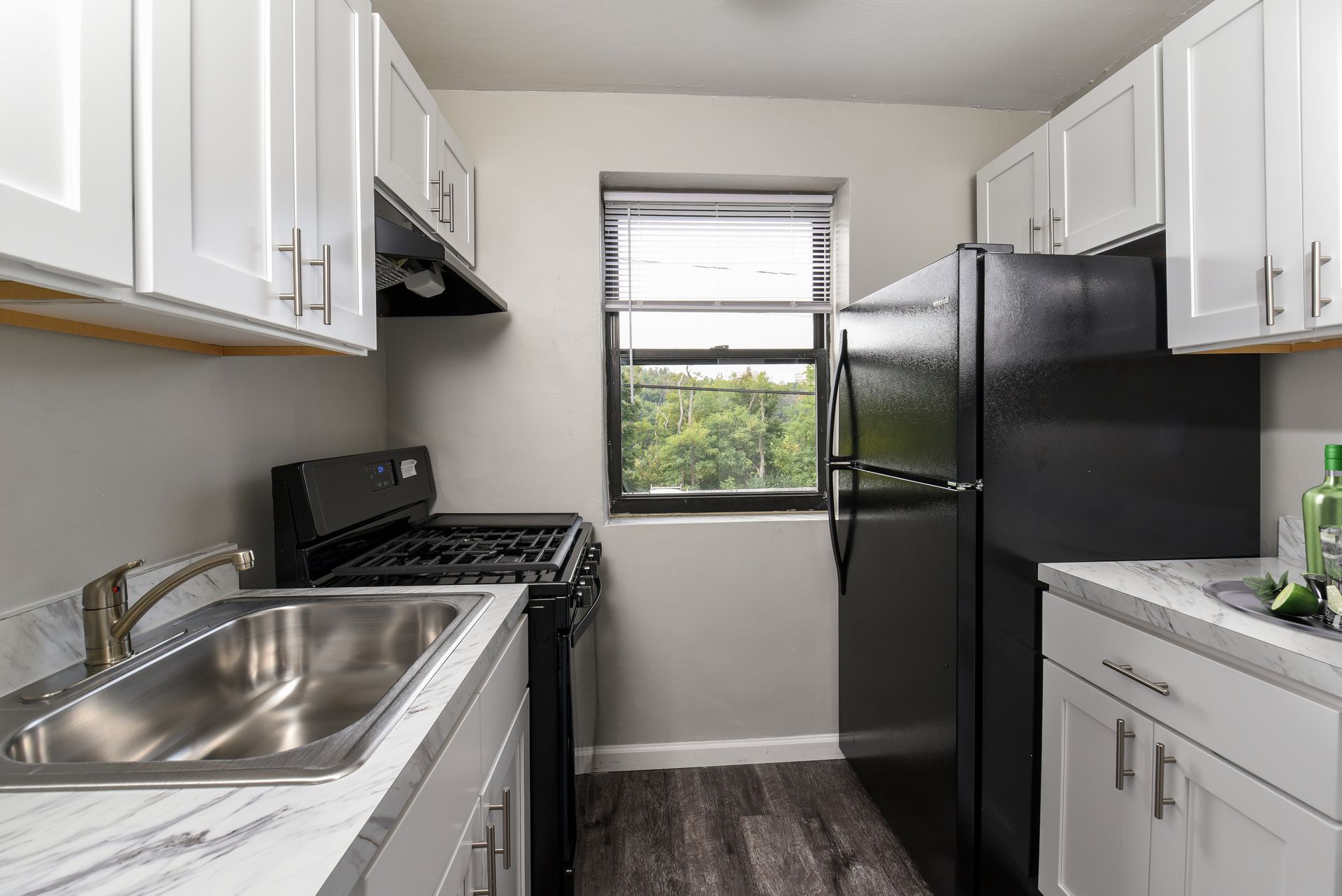 Kitchen with white cabinets, black appliances, and a window.