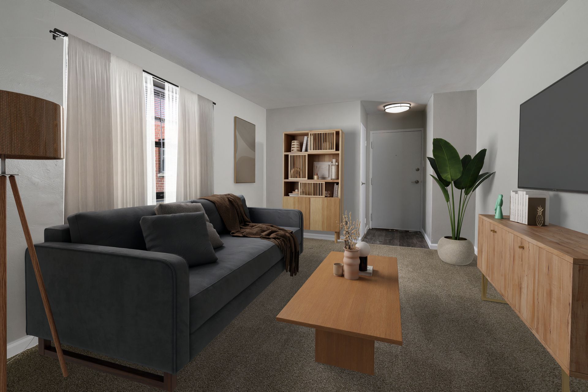 Living room with gray sofa, wooden furniture, and potted plant.
