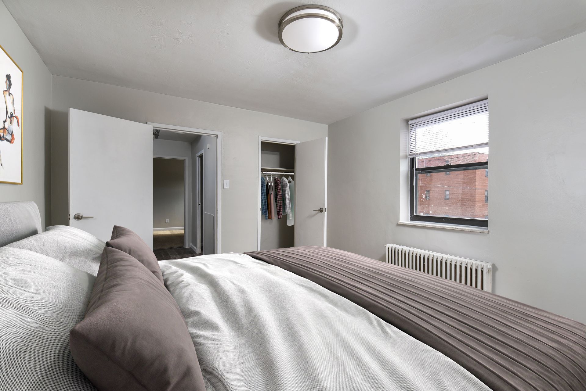 Bedroom with bed, closet, window, doors, and ceiling light.
