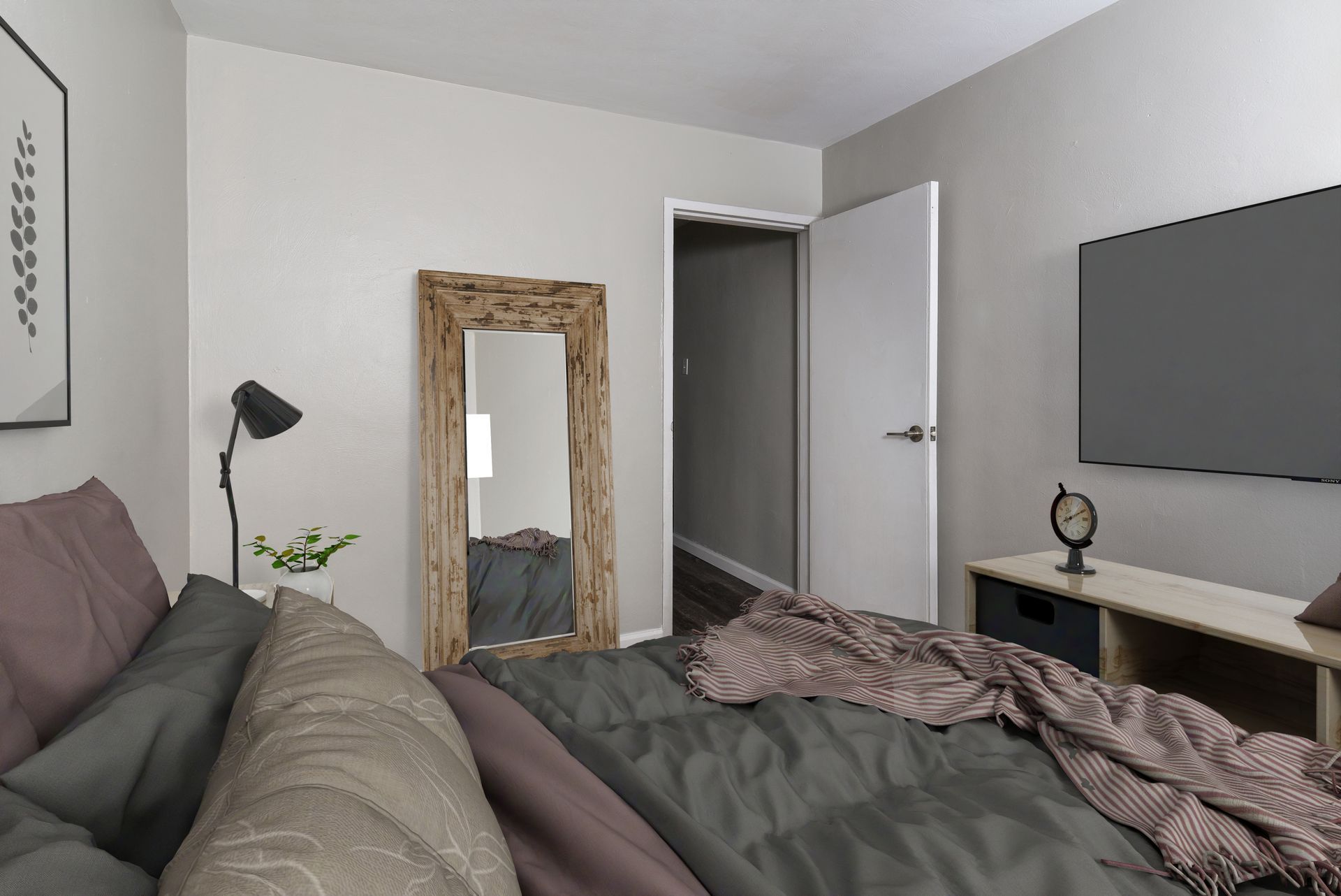 Bedroom with bed, mirror, TV, and open door to hallway. Gray and mauve color scheme.