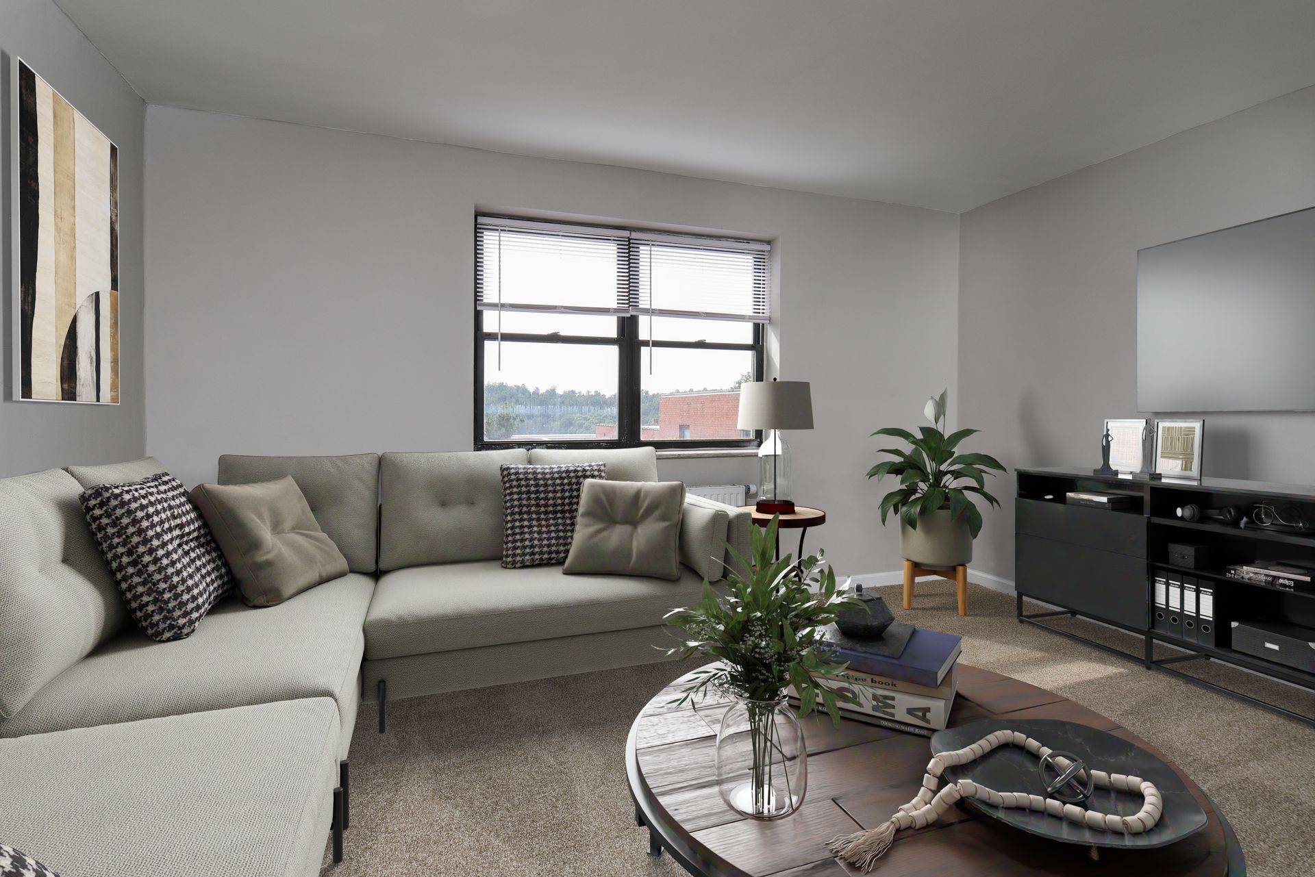 Cozy living room with a sectional sofa, a coffee table, and a TV; natural light streams in through the window.