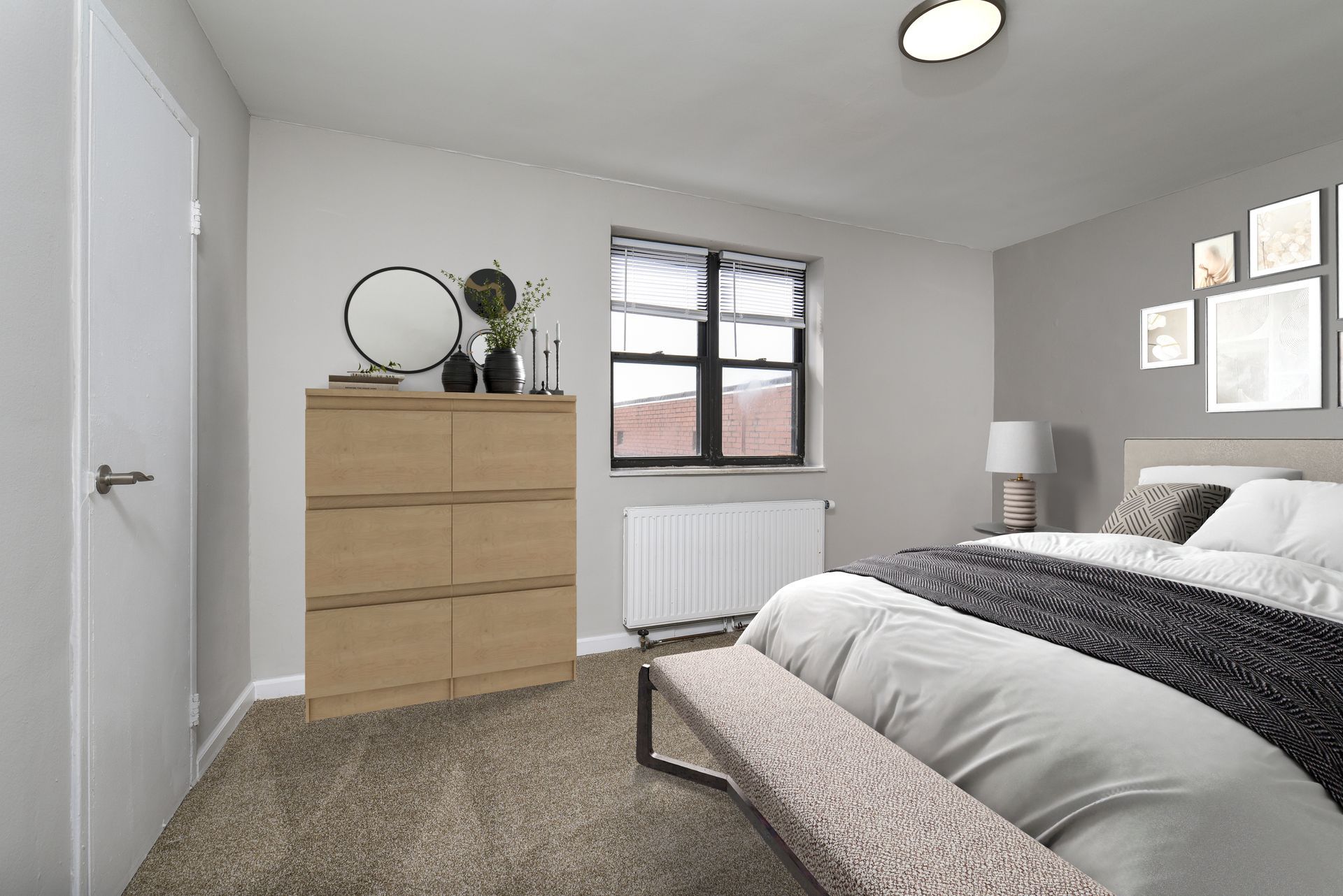 Bedroom with bed, dresser, bench, window, and wall art. Neutral colors, natural light.