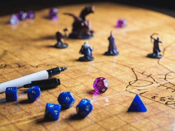 D&D game setup: miniature figurines, dice (blue, purple), pen, and grid map on a table.