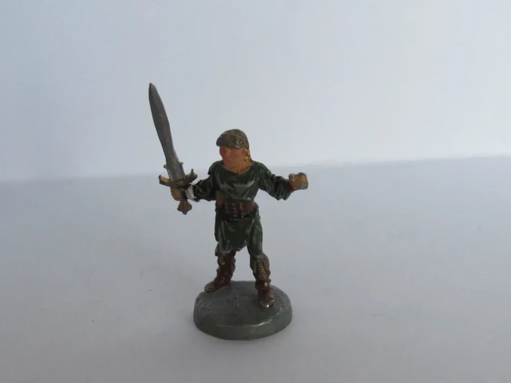 Miniature figure of a warrior holding a sword, wearing green tunic and brown boots, on a gray base.