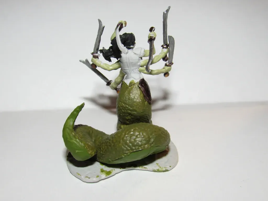 Miniature of a serpent-bodied humanoid with multiple arms holding swords. Green snake lower body, pale skin.