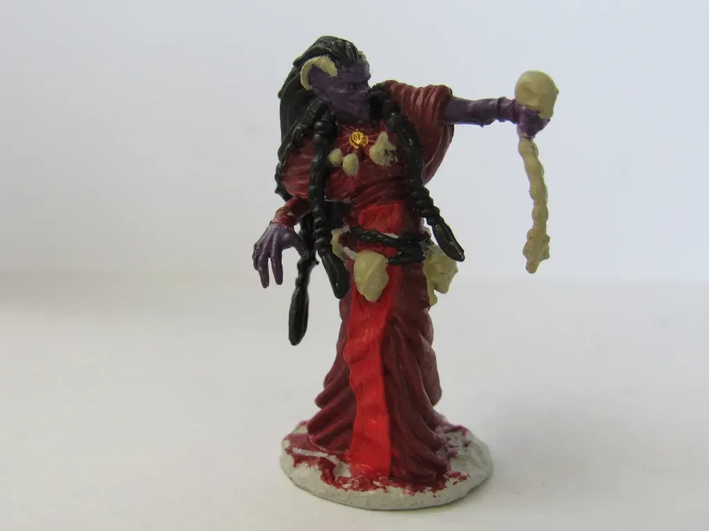 Purple-skinned fantasy figure in red robes holding a bone, with horns and dark hair.