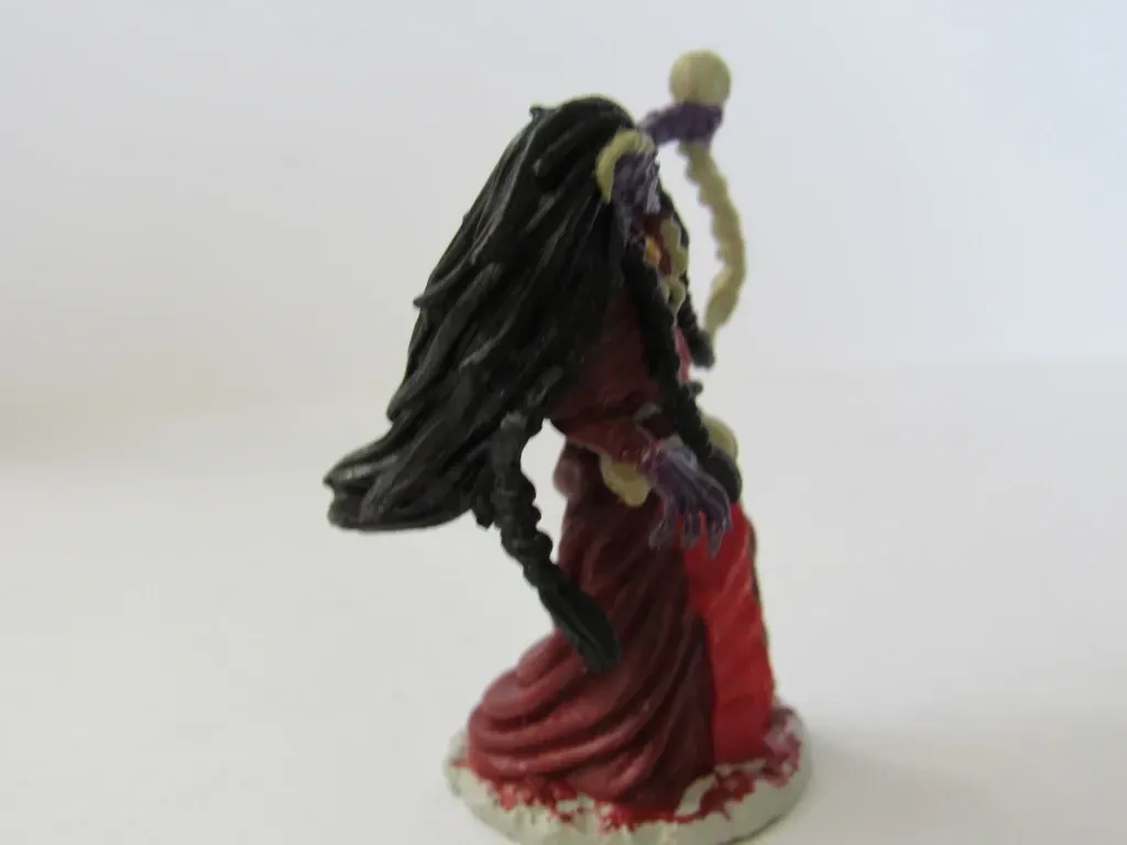 Miniature of a robed, purple-skinned figure with long black hair, holding a staff.