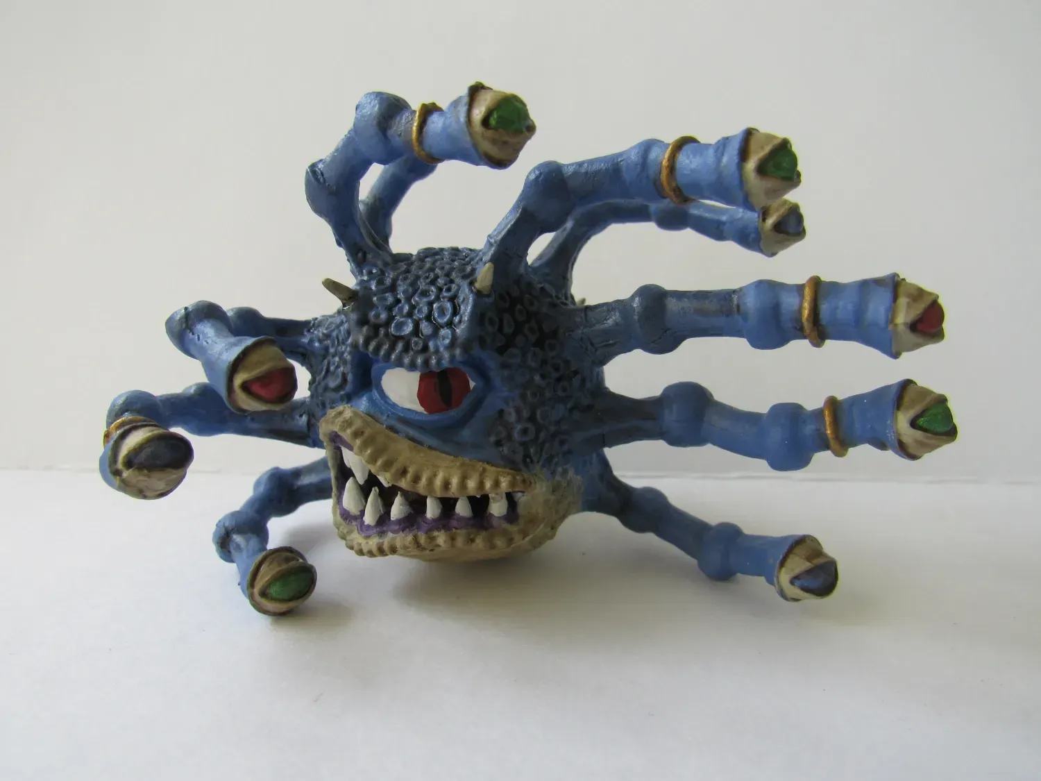 Blue and tan monster figurine with multiple eye stalks and a menacing grin.