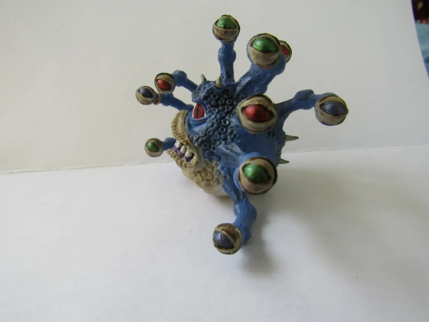 Blue and tan toy creature with multiple eyes and sharp teeth.
