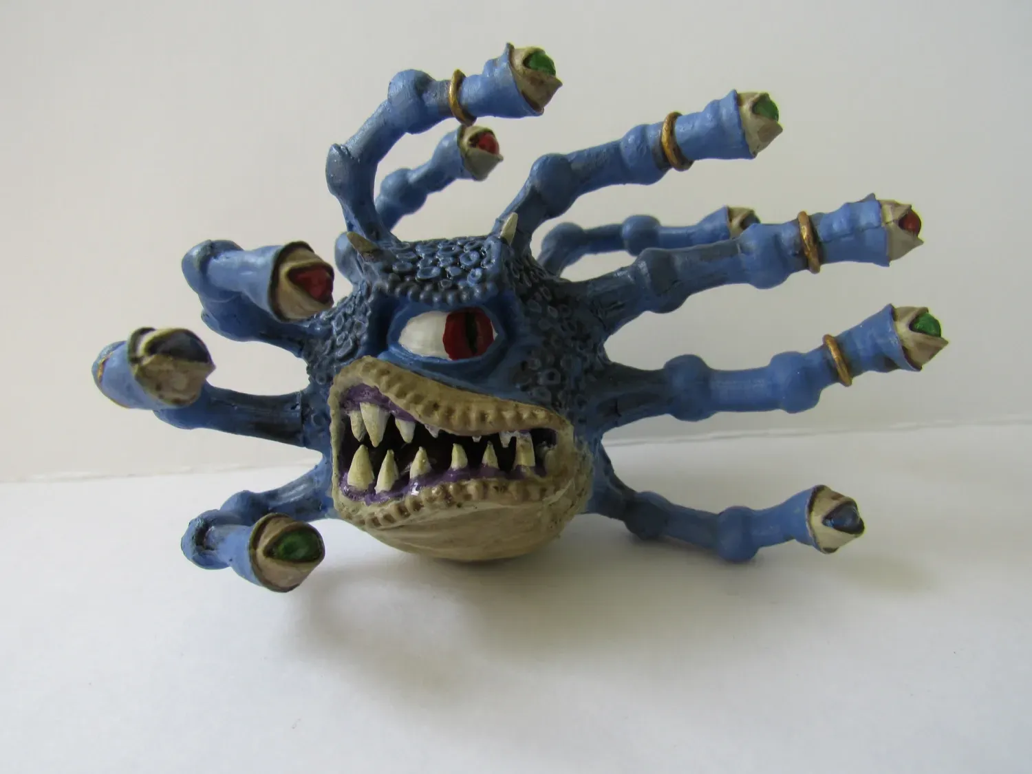 Blue toy monster with multiple eyes, teeth, and tentacles.