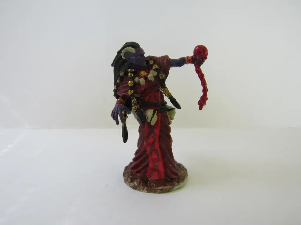 Miniature figure of a dark-skinned sorceress in red robes holding a bloody tentacle.
