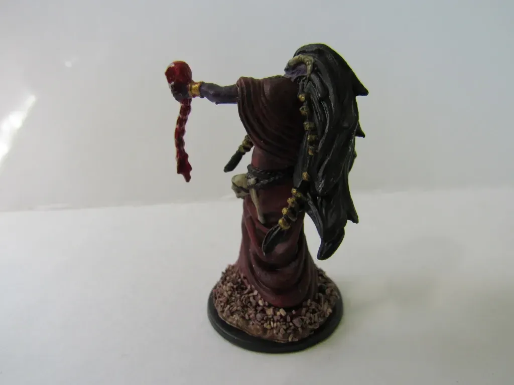 Miniature figure of a robed sorceress with long dark hair holding a bloody, red braid.