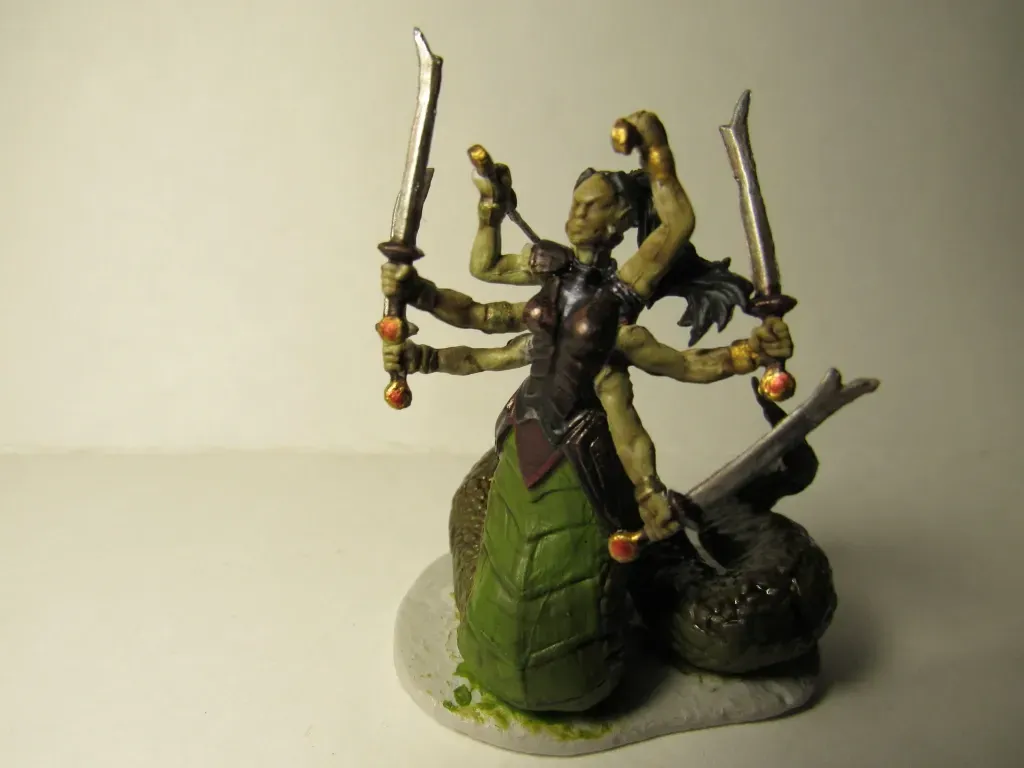 Six-armed green-skinned naga wielding swords. Dark armor, snake tail, on a stone base.