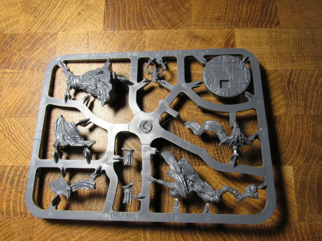 Plastic model sprue with various miniature monster components on a wooden surface.
