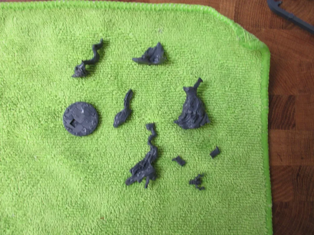 Dark gray plastic game pieces on a green cloth, arranged on a wooden surface.