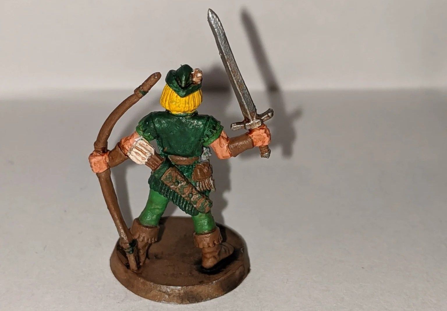 Miniature figure of an archer in green with a sword and bow.