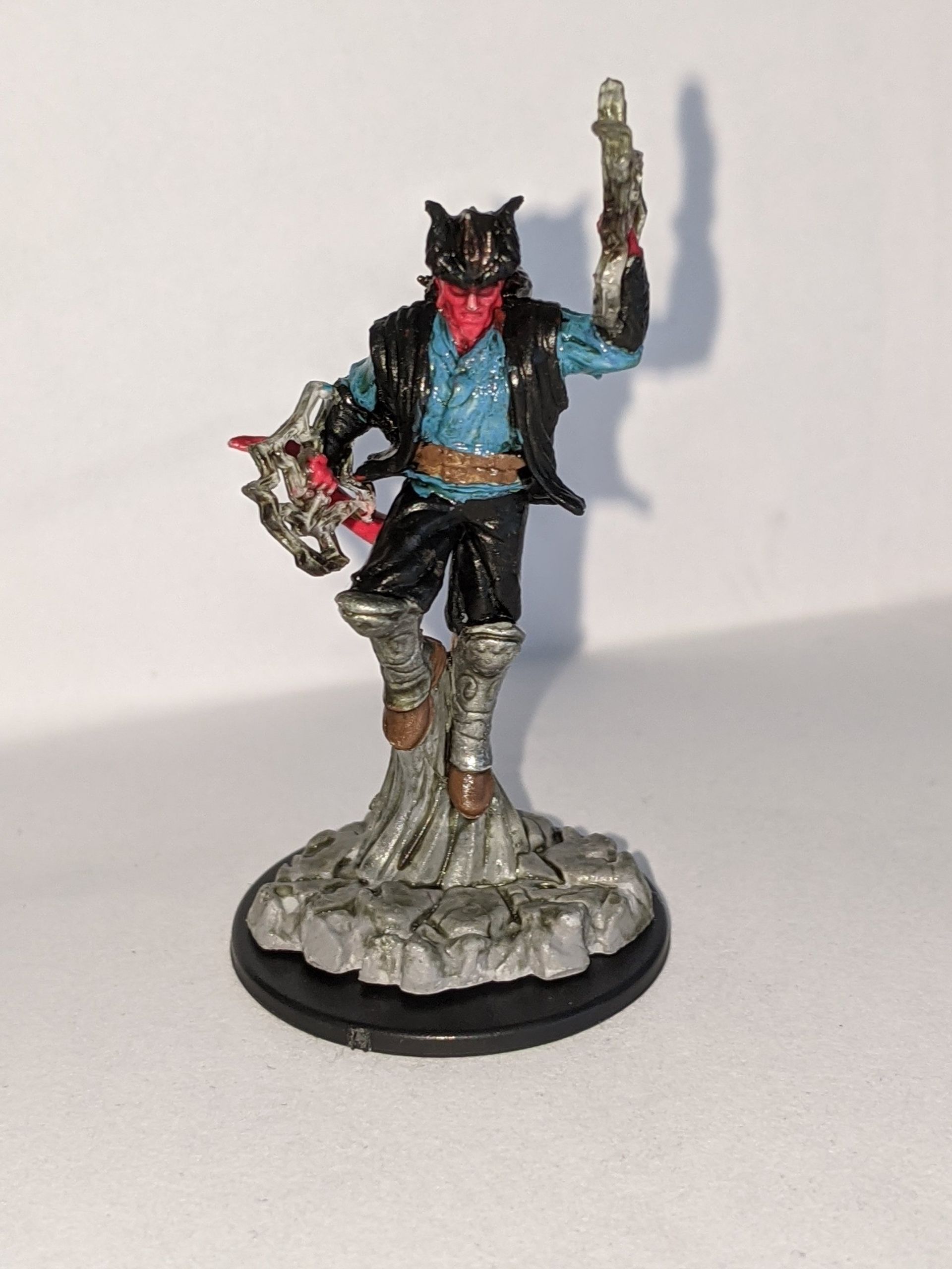 Miniature figure of a red demon-like character with a gun raised, standing on a rocky base.