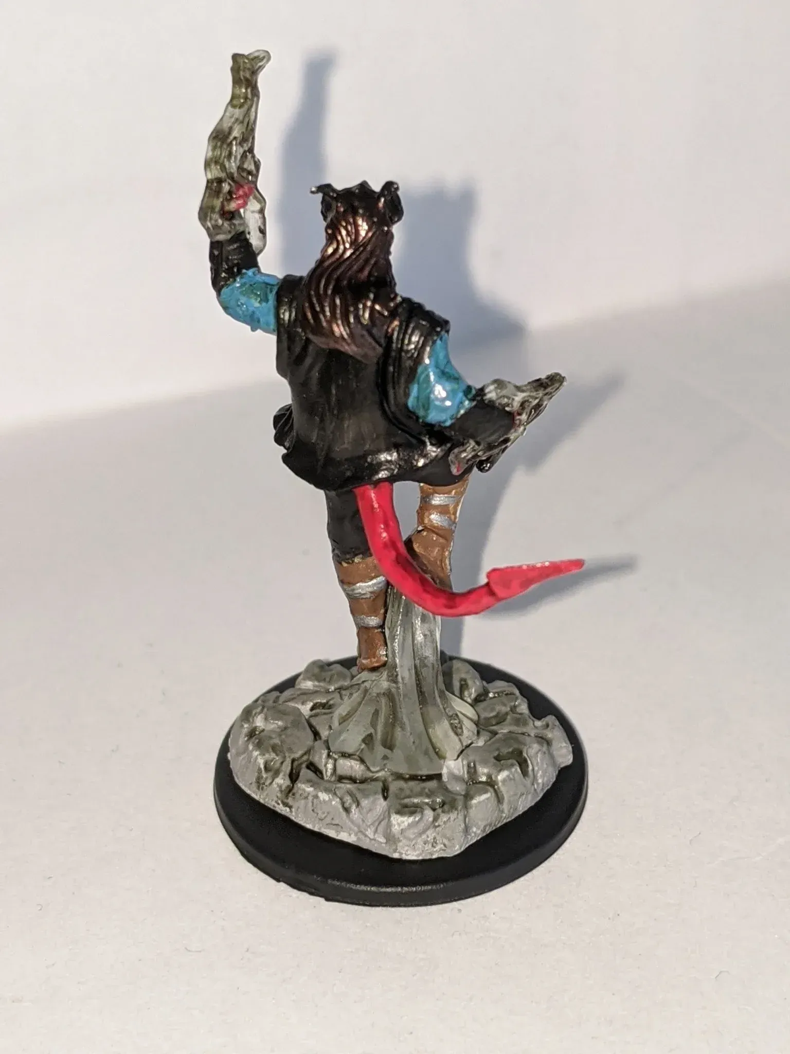 Miniature of a horned figure with a red tail, holding a bottle up.