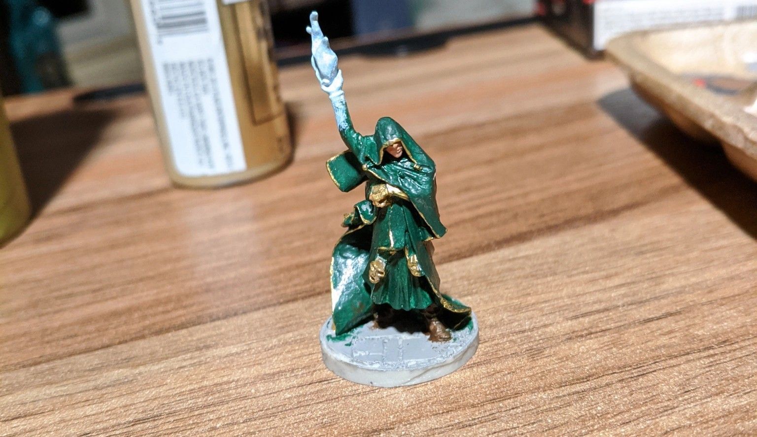 Miniature figure of a green-robed wizard with a staff, on a wooden table.