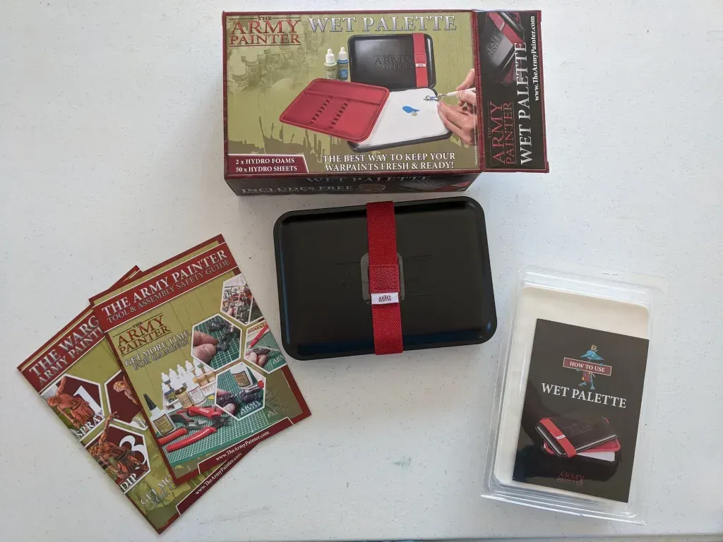 A wet palette set by The Army Painter: box, closed container, instructions, and accessories on a white surface.