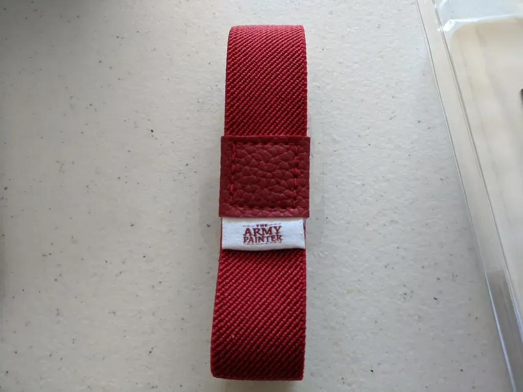 Red fabric watch strap with leather loop, white label that reads