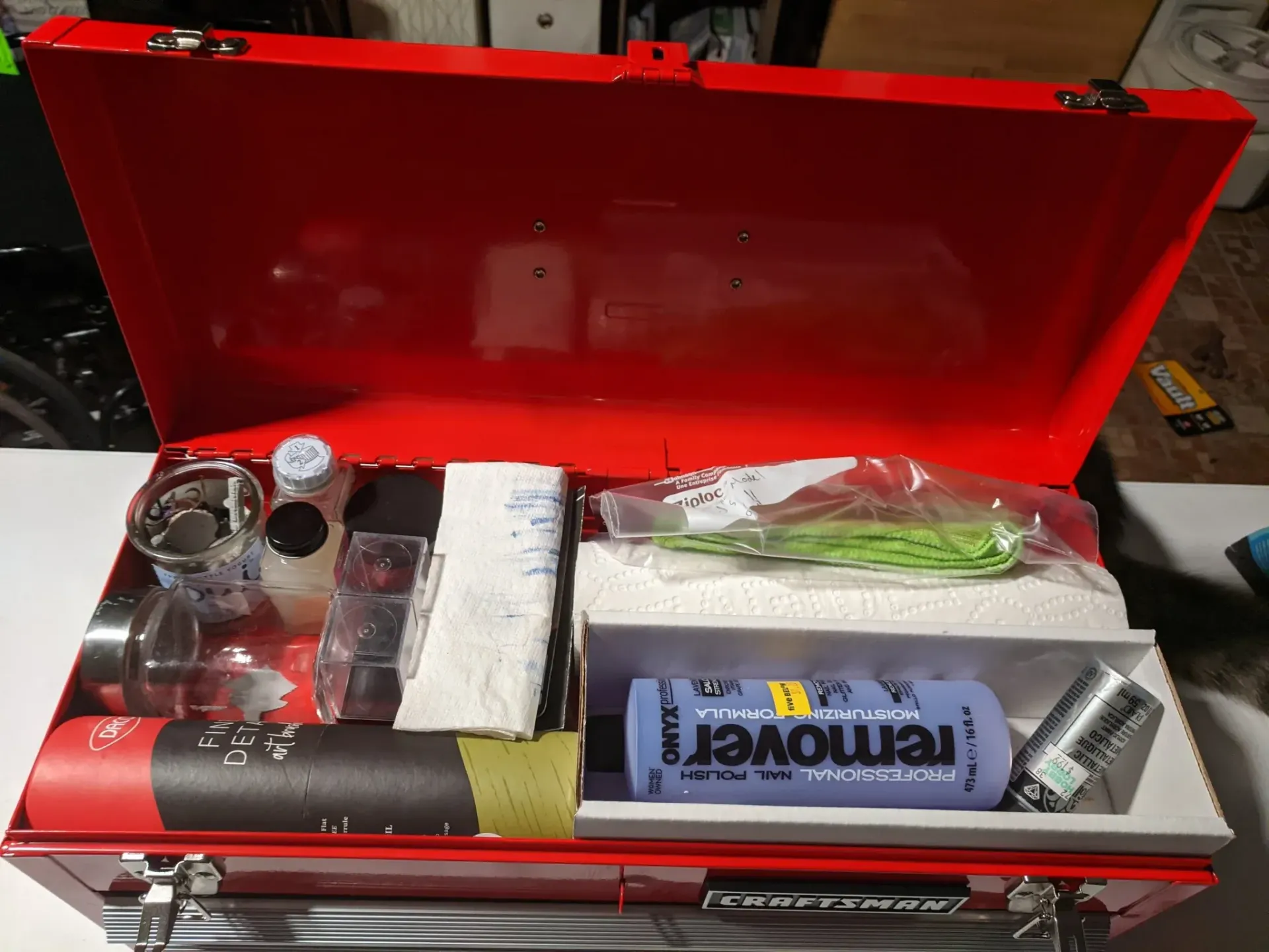 Red toolbox open, filled with various tools, chemicals, and containers.
