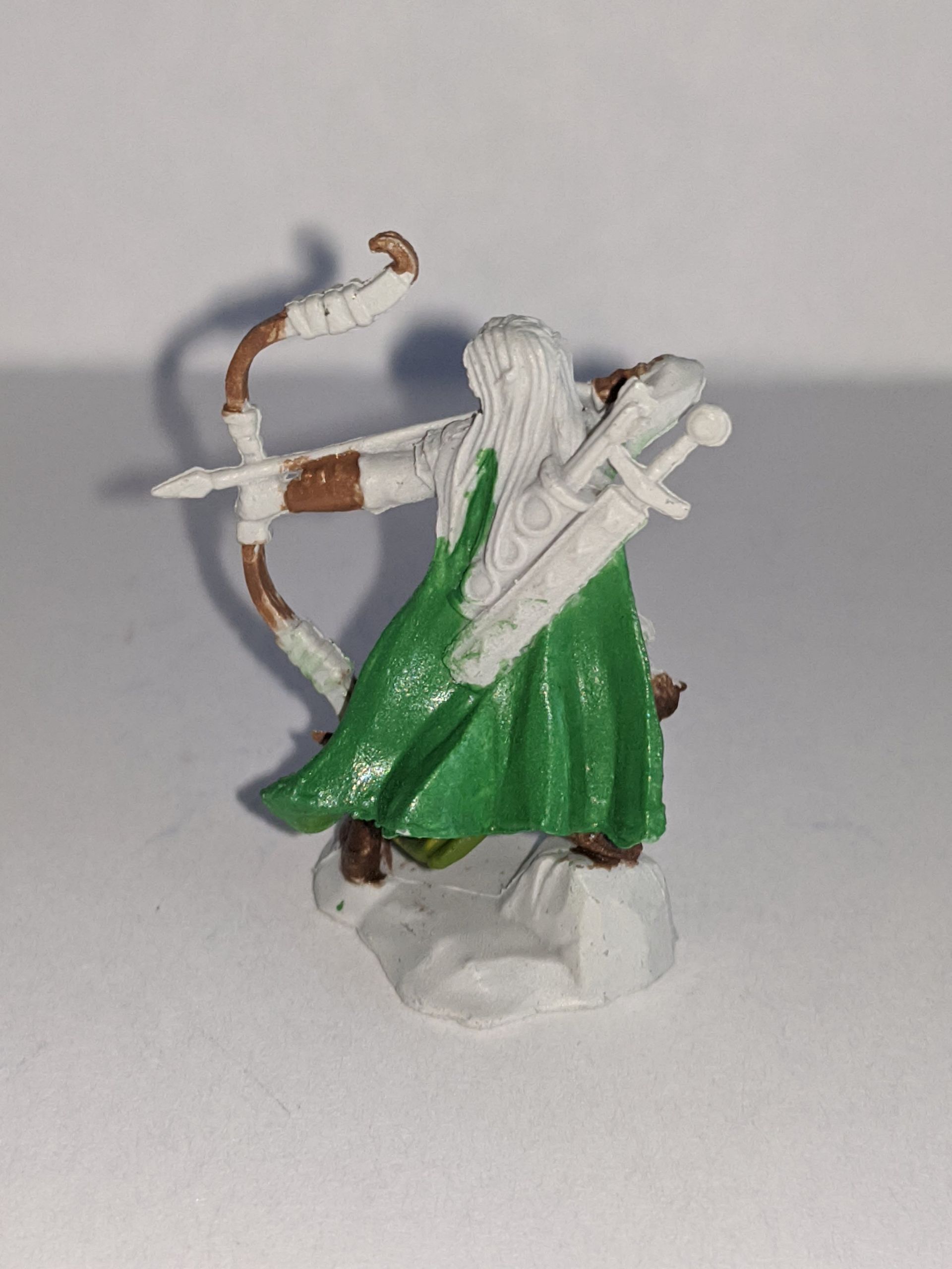 Miniature figure of an elf archer with a green cloak, drawing a bow.