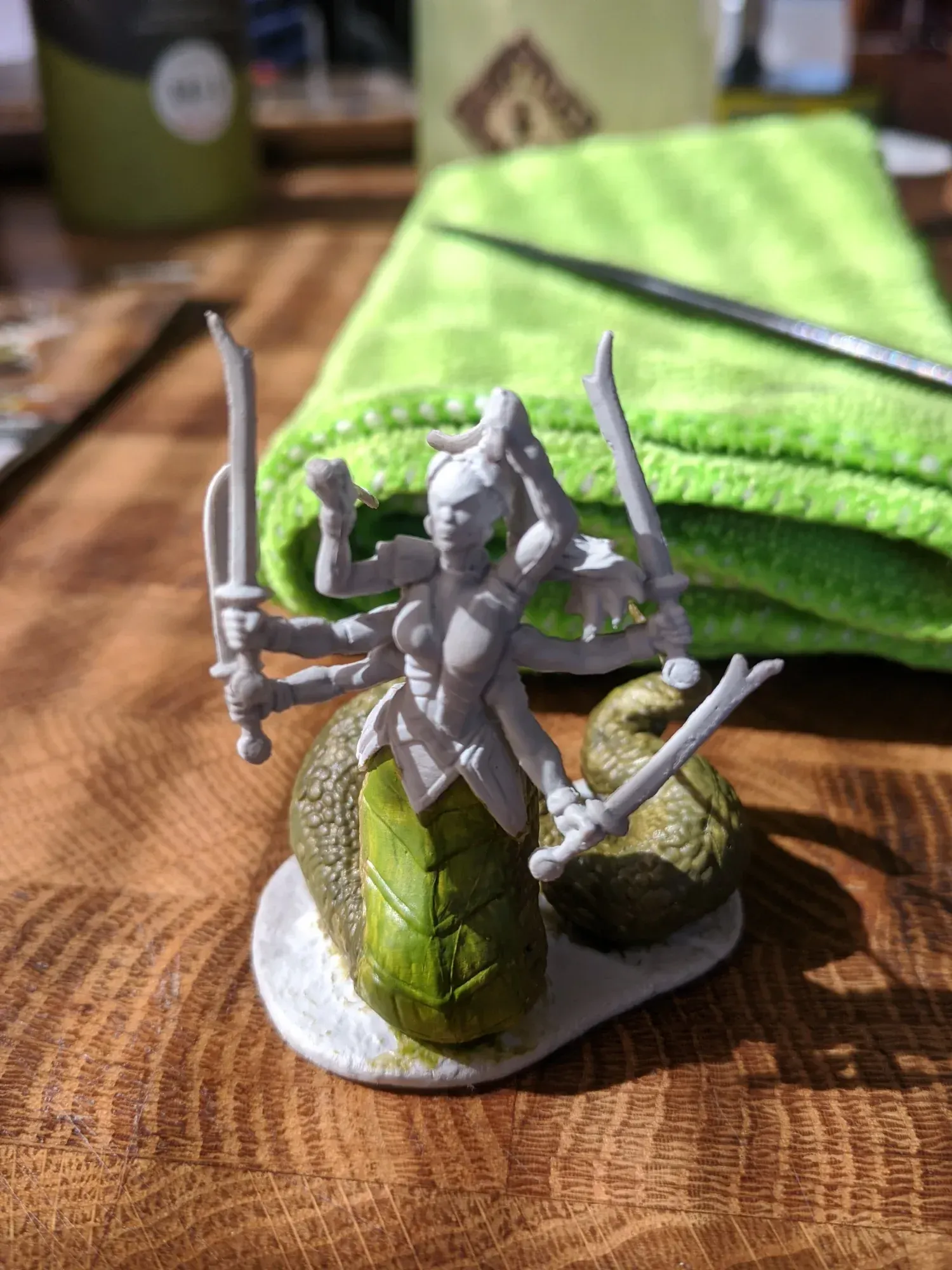 A miniature figure of a woman with multiple arms holding swords, atop a snake-like base.