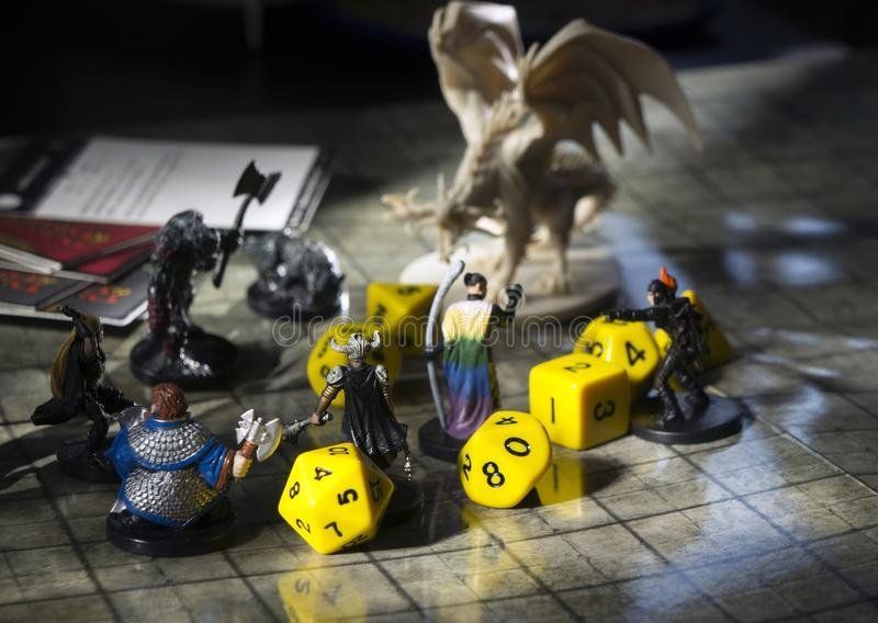 D&D game setup. Miniatures of characters and dragon with yellow dice on a game map.