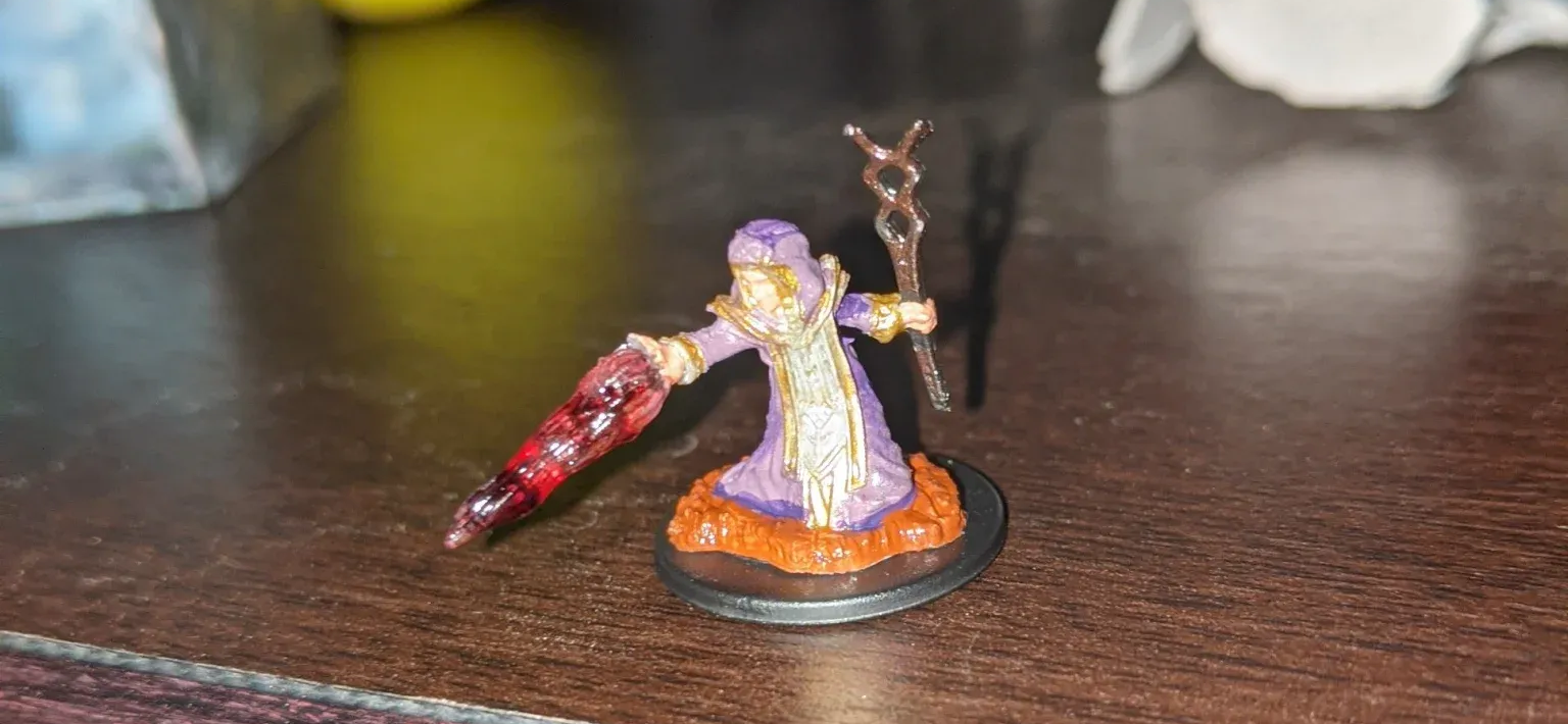 A purple wizard mini-figure with a bloody arm stands on an orange base and holds a staff.