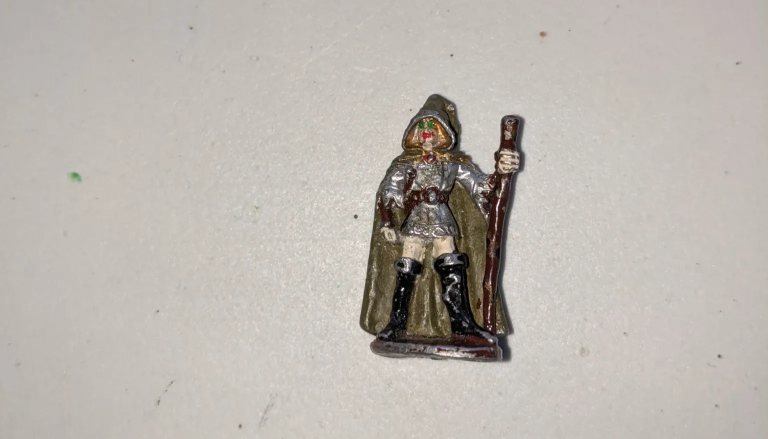 Miniature fantasy figure wearing armor and a cape, holding a staff.