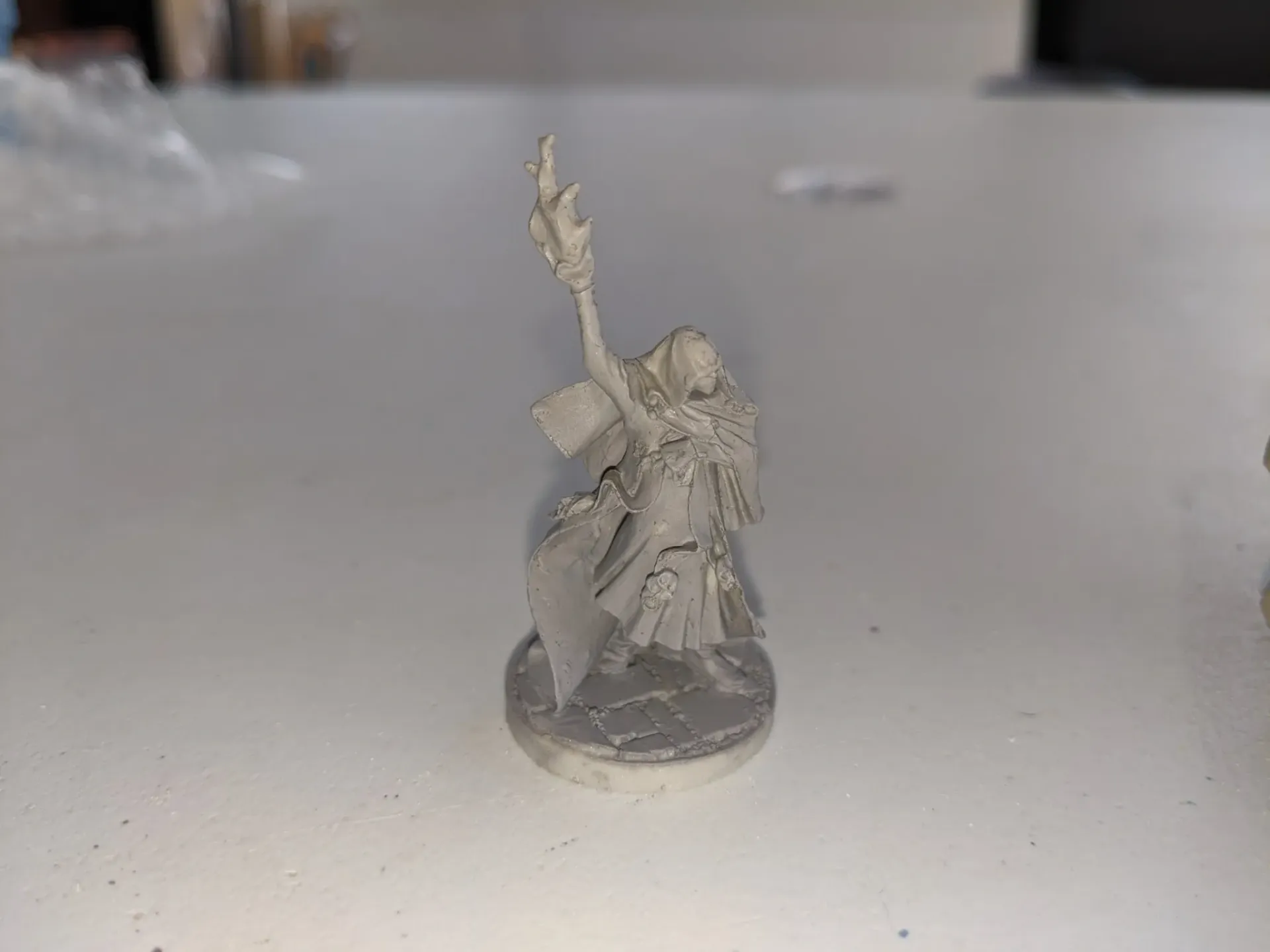 Miniature figure of a robed person with a staff and book on a round base.