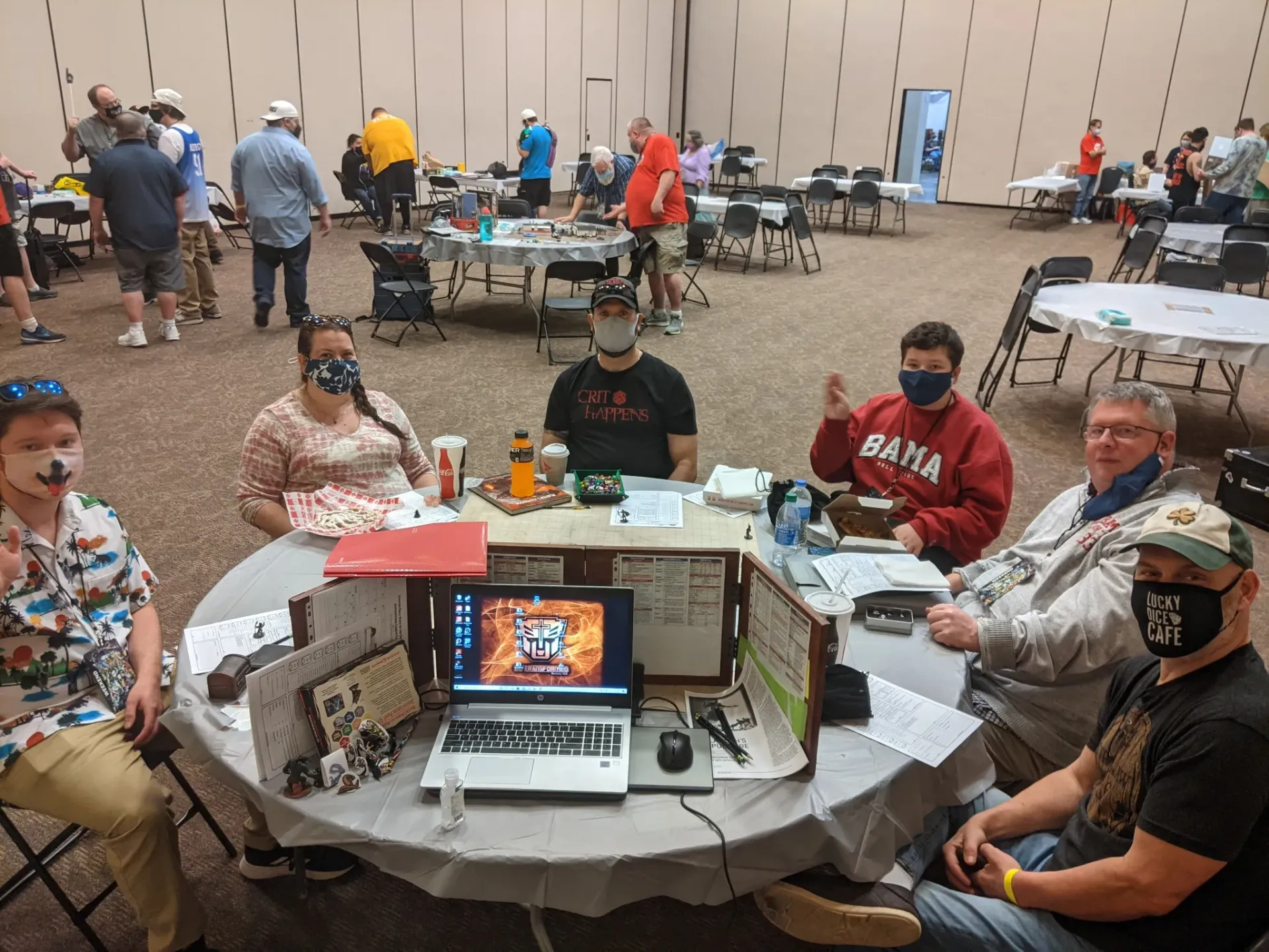 Before the game began! Group of masked people at a table, possibly event staff, with laptops and supplies in a large hall.