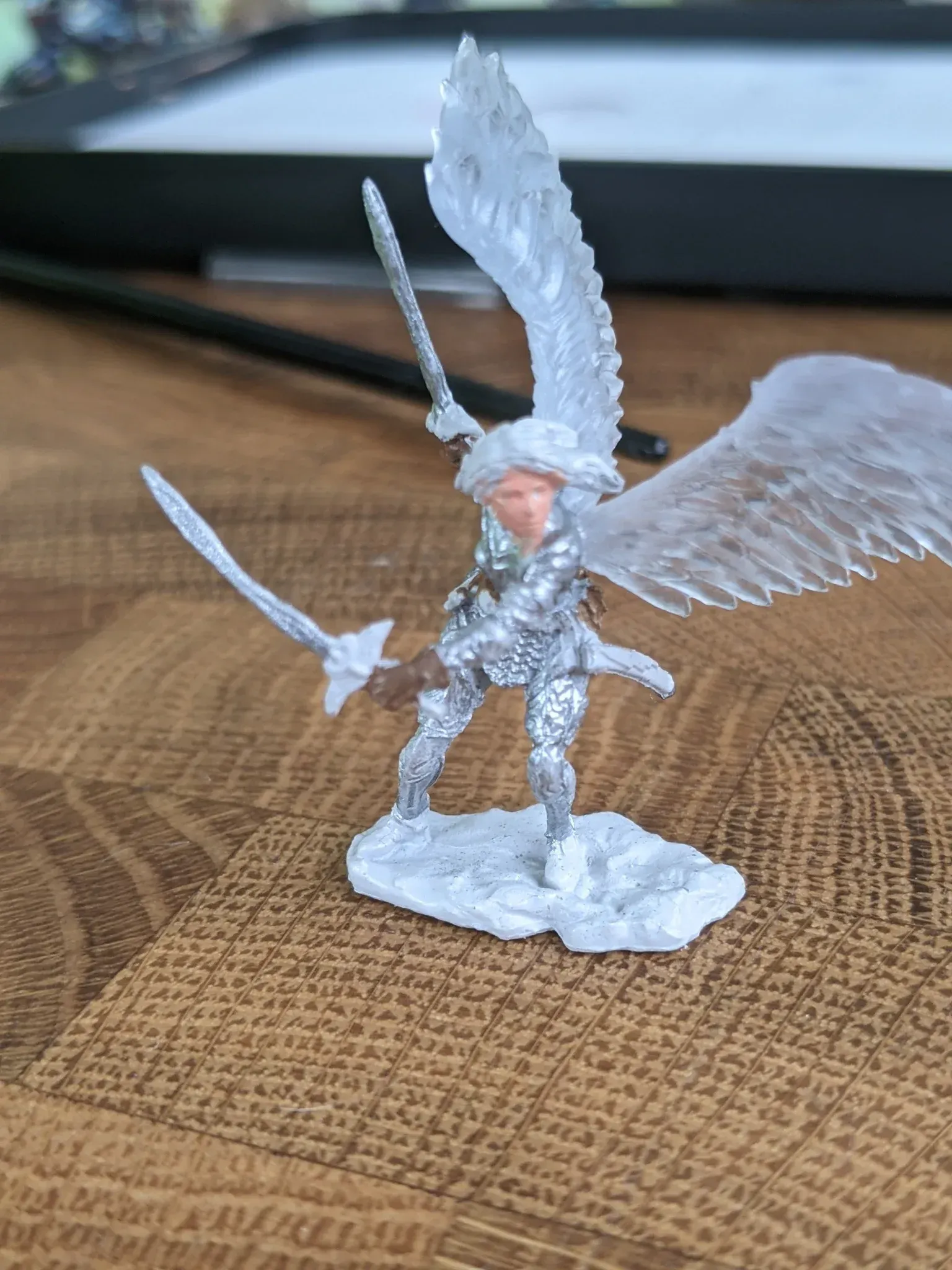 Miniature angel with silver armor, wielding swords, wings spread, standing on snowy base.