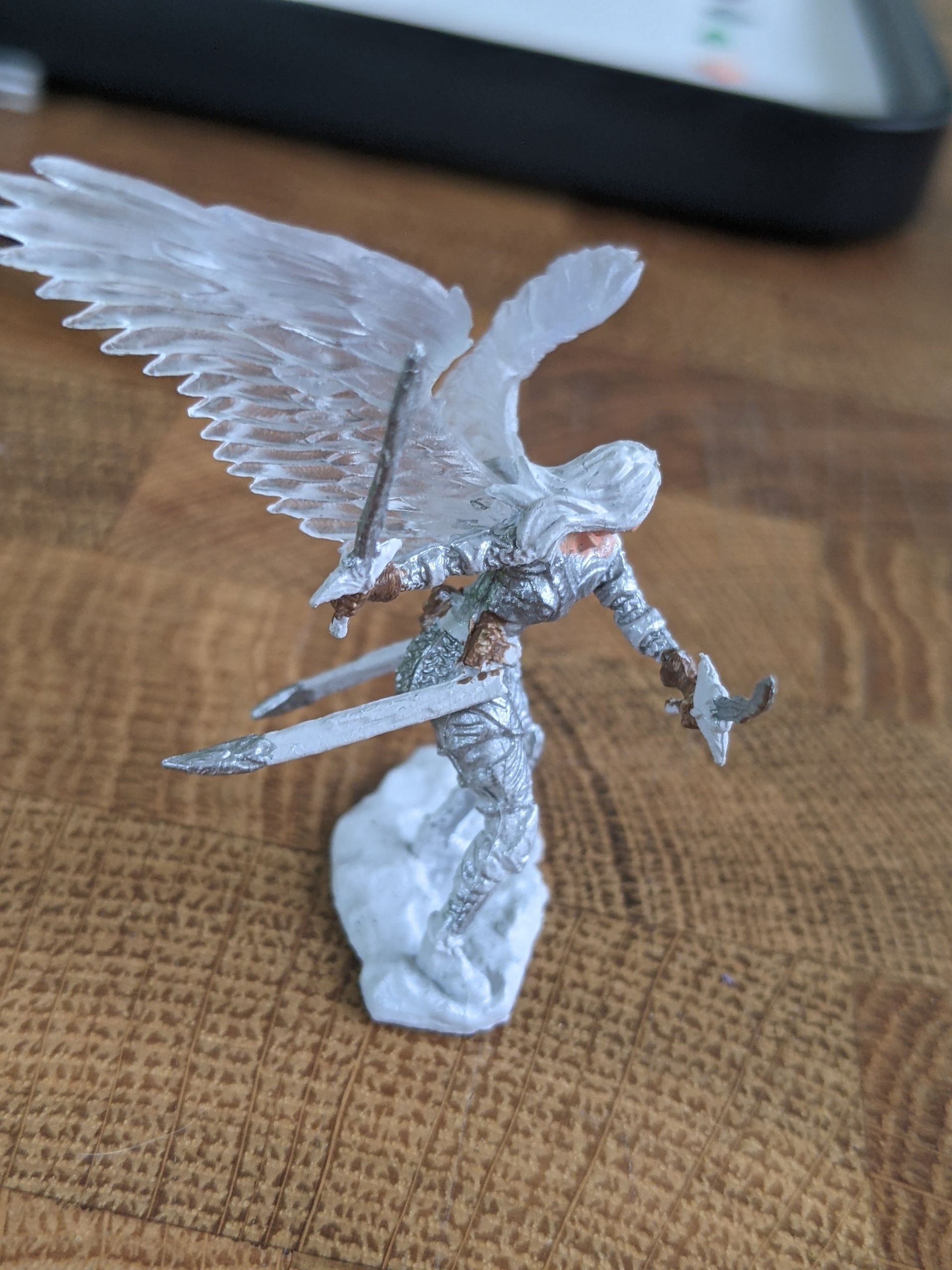 Silver angel miniature with spread wings, swords, and a snowy base.