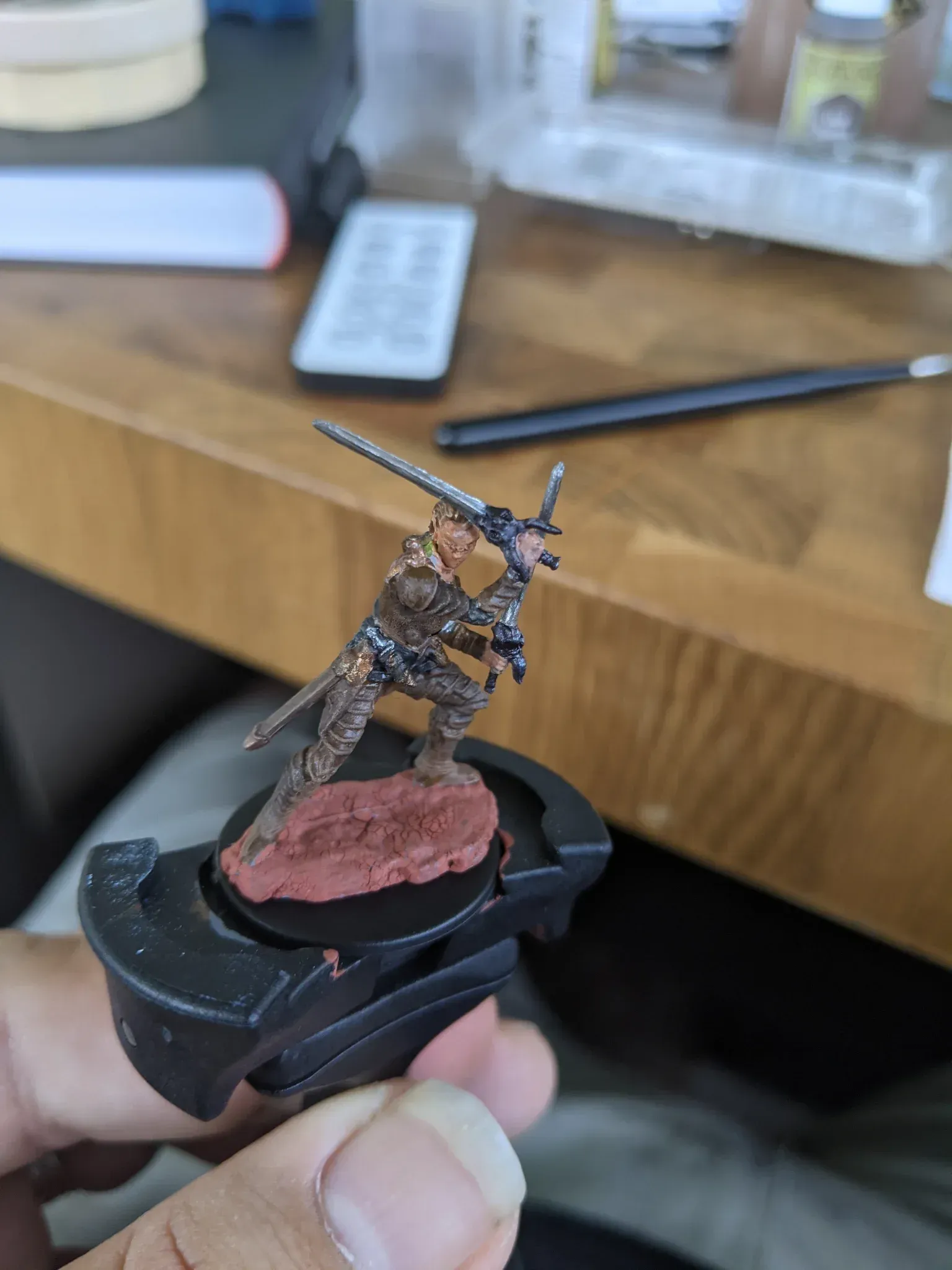 Miniature figure of a warrior with two swords, painted on a red-brown base.