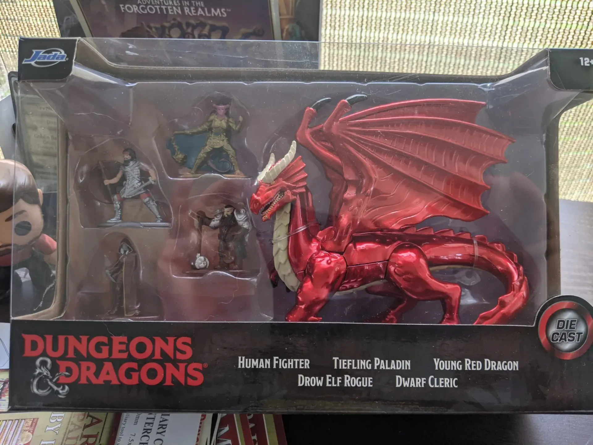 D&D boxed set with red dragon and miniature figures: warrior, mage, cleric. Shiny red dragon, plastic figures.