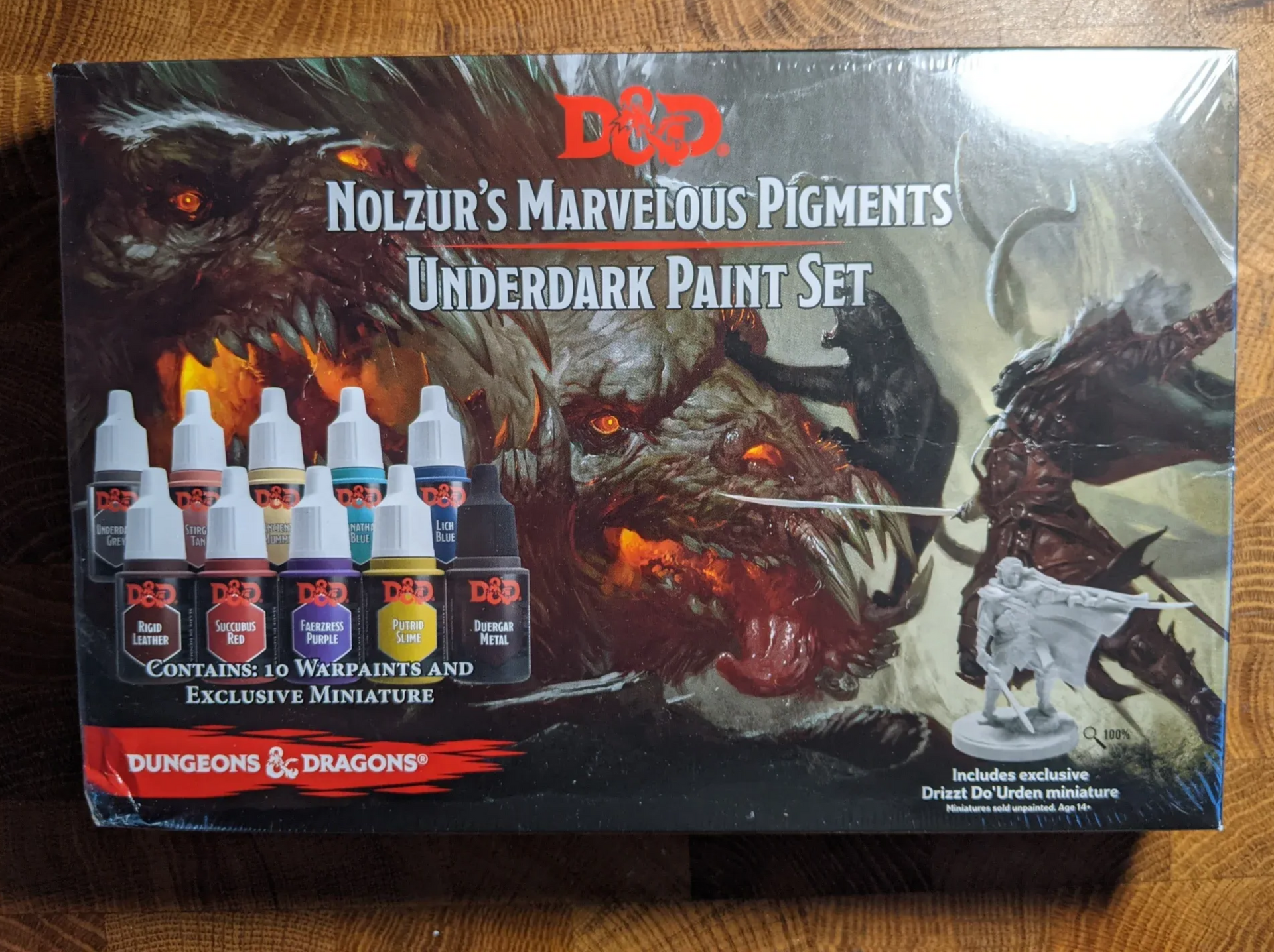 D&D paint set: Nolzur's Marvelous Pigments, Undermine; featuring a monster with glowing eyes, paints, and a miniature.