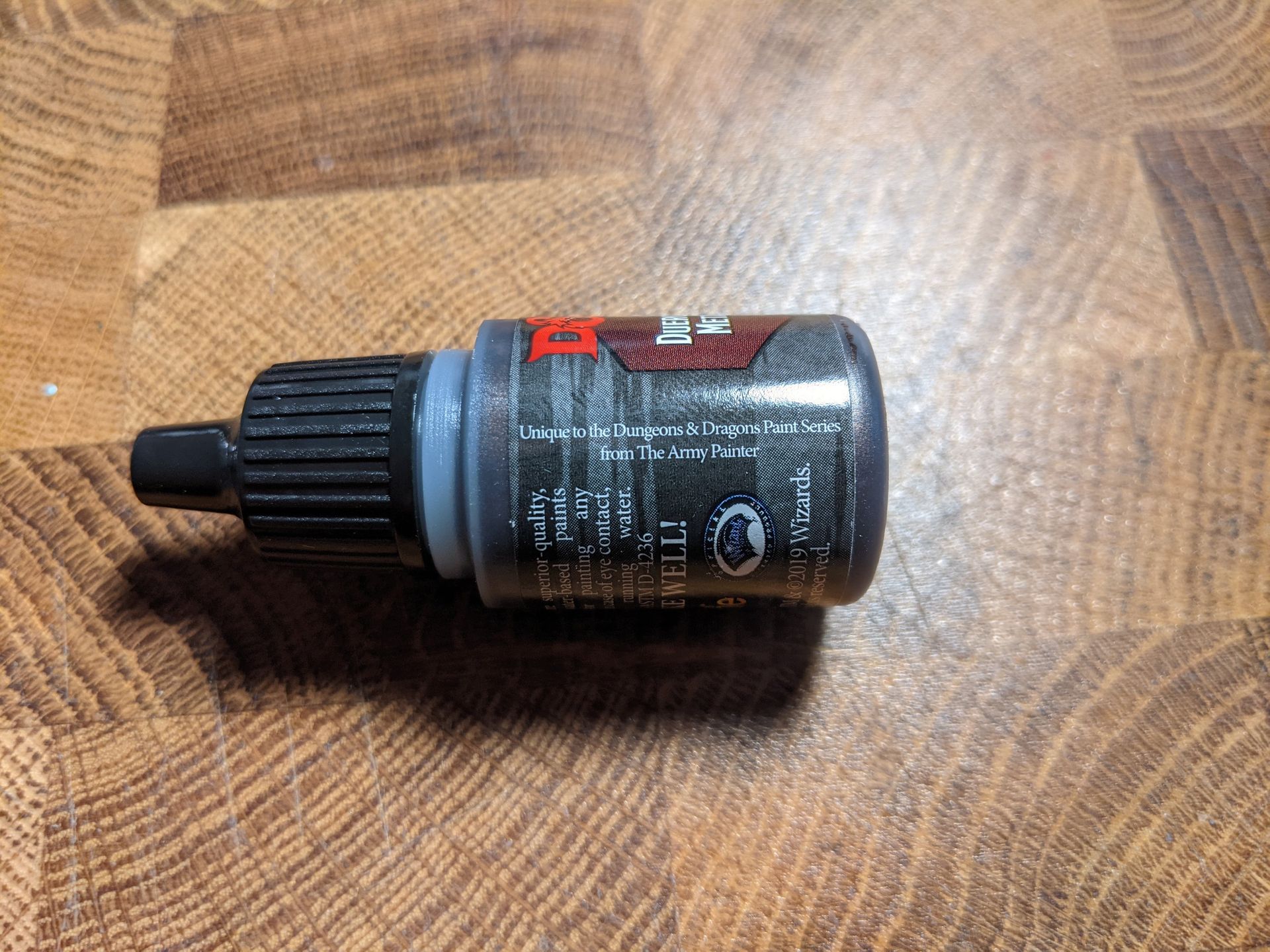 A black bottle of adhesive on a wooden surface, with a dark label.