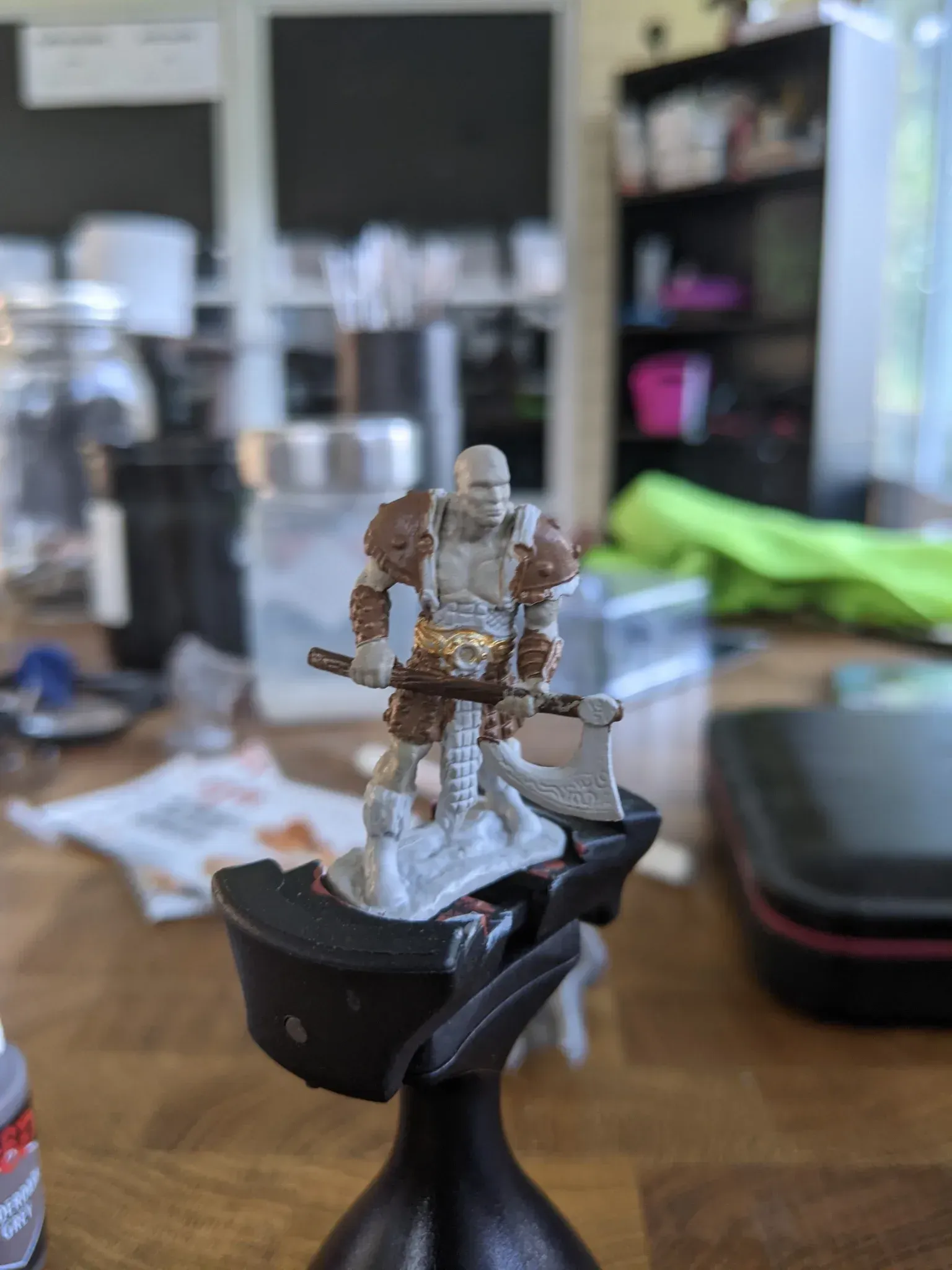 Miniature figurine of a warrior with an axe, partially painted. Beige armor, brown accents.