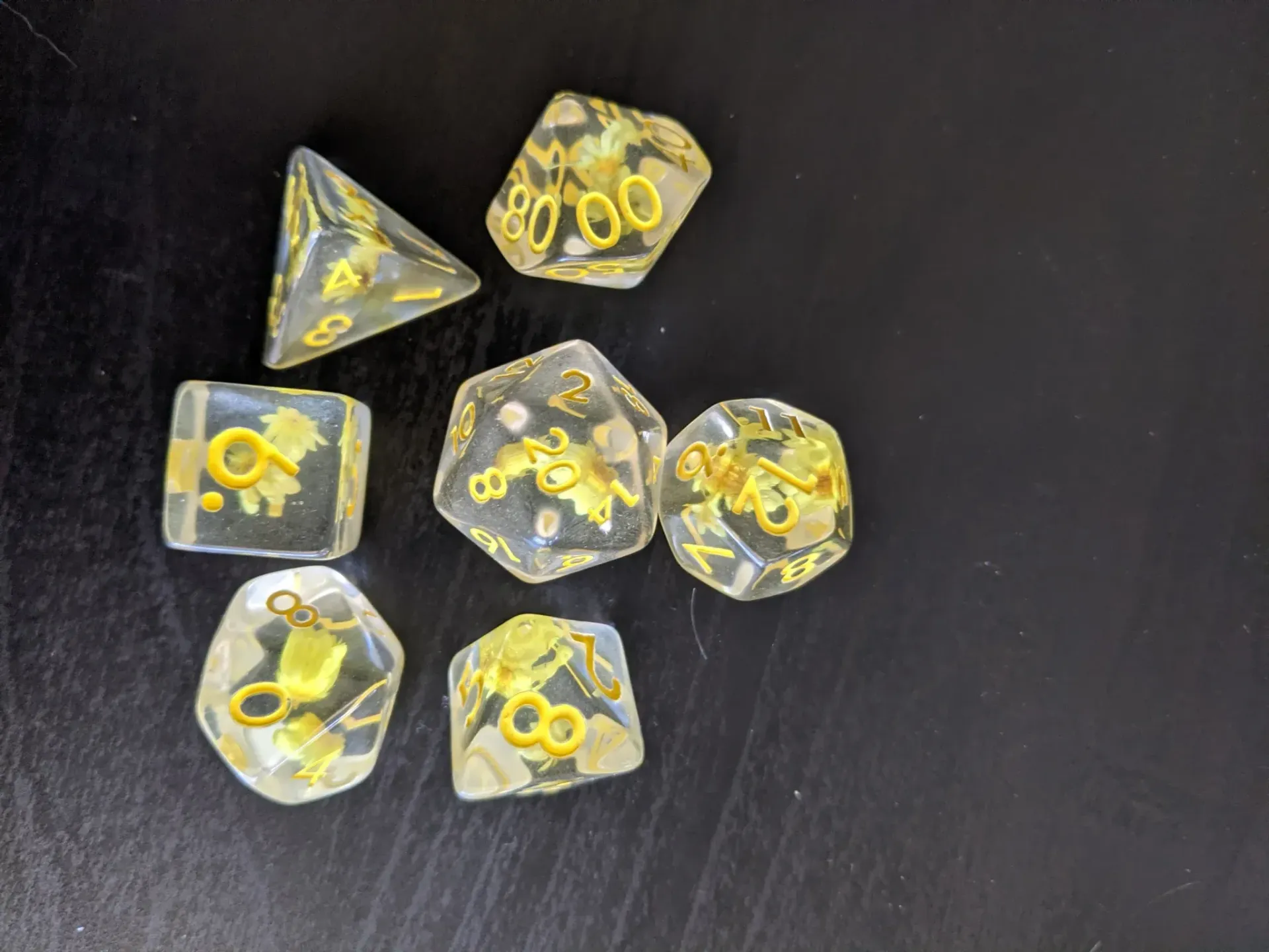 Set of clear dice with gold numbers and accents on a black surface.