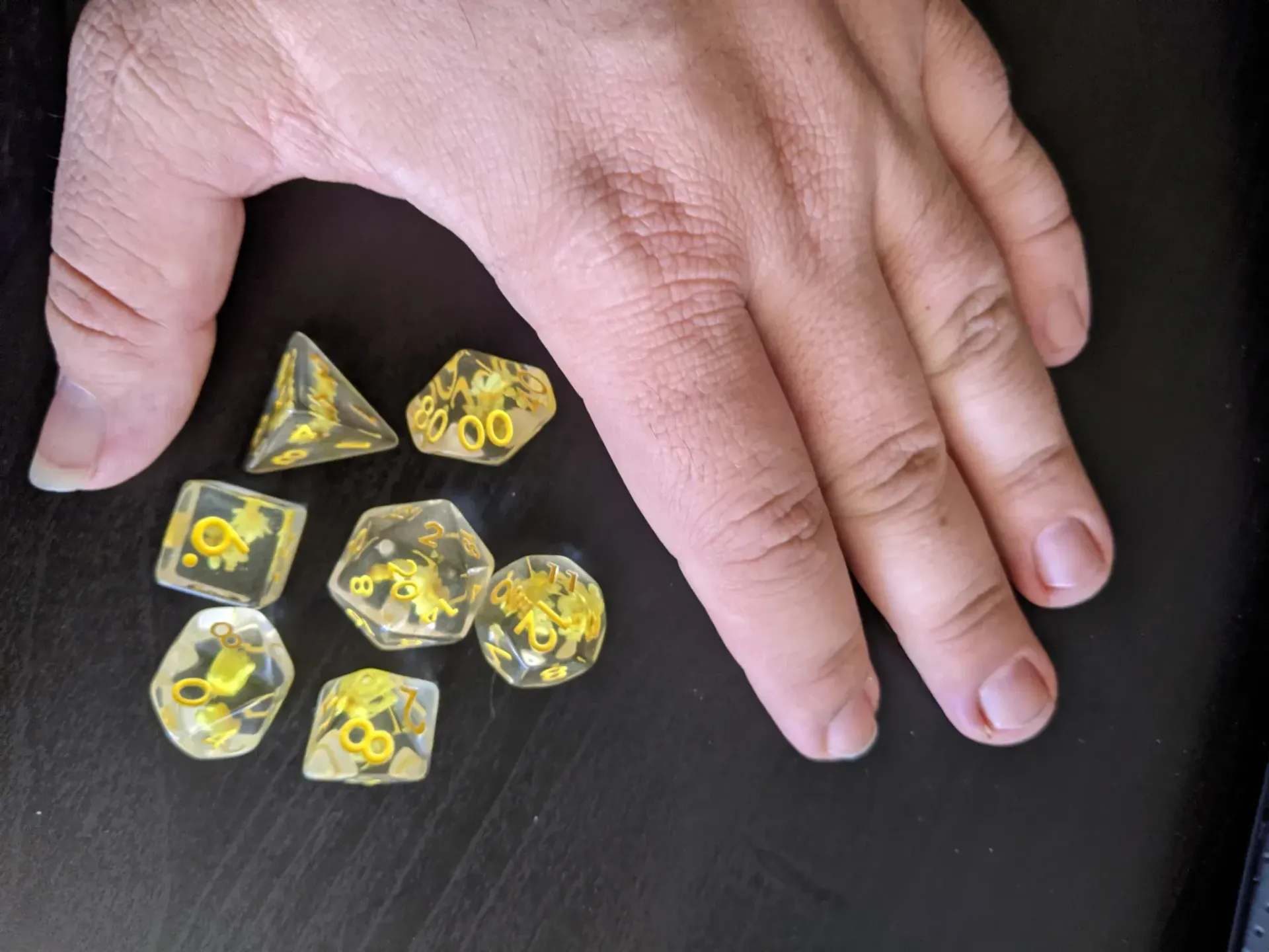 Hand next to a set of yellow dice.