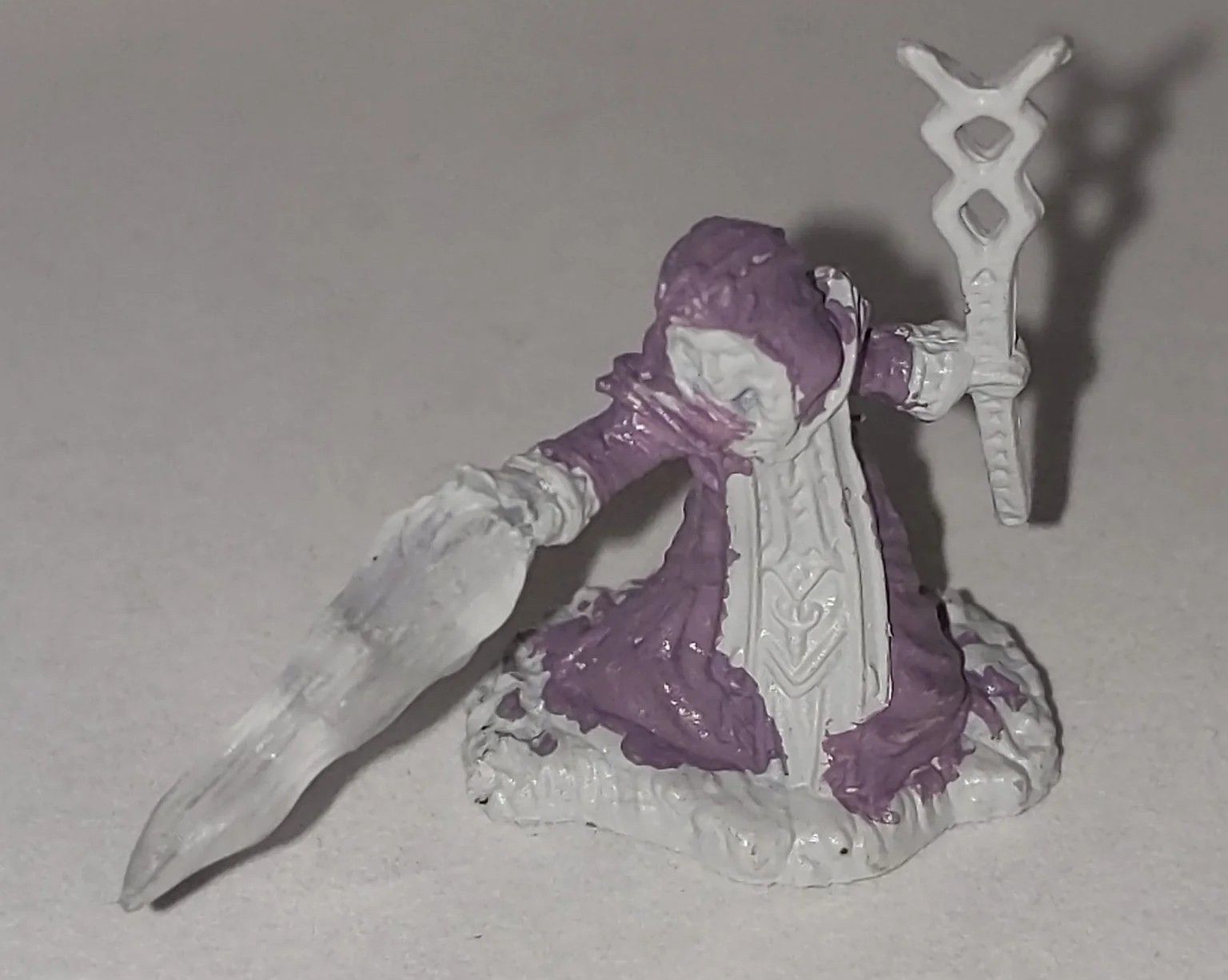 Miniature figure of a robed mage wielding a staff, casting an icy spell. Mostly purple and white