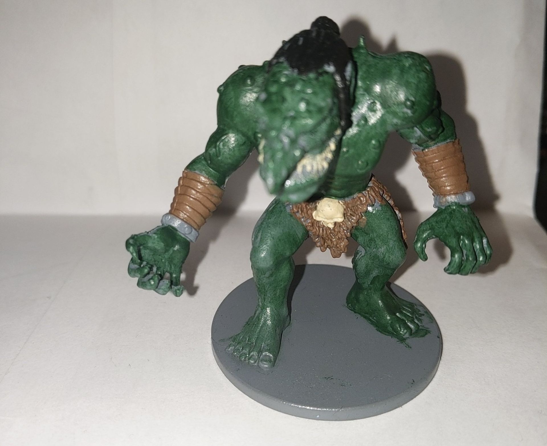 Green fantasy creature figurine with a brutish stance, standing on a grey base.