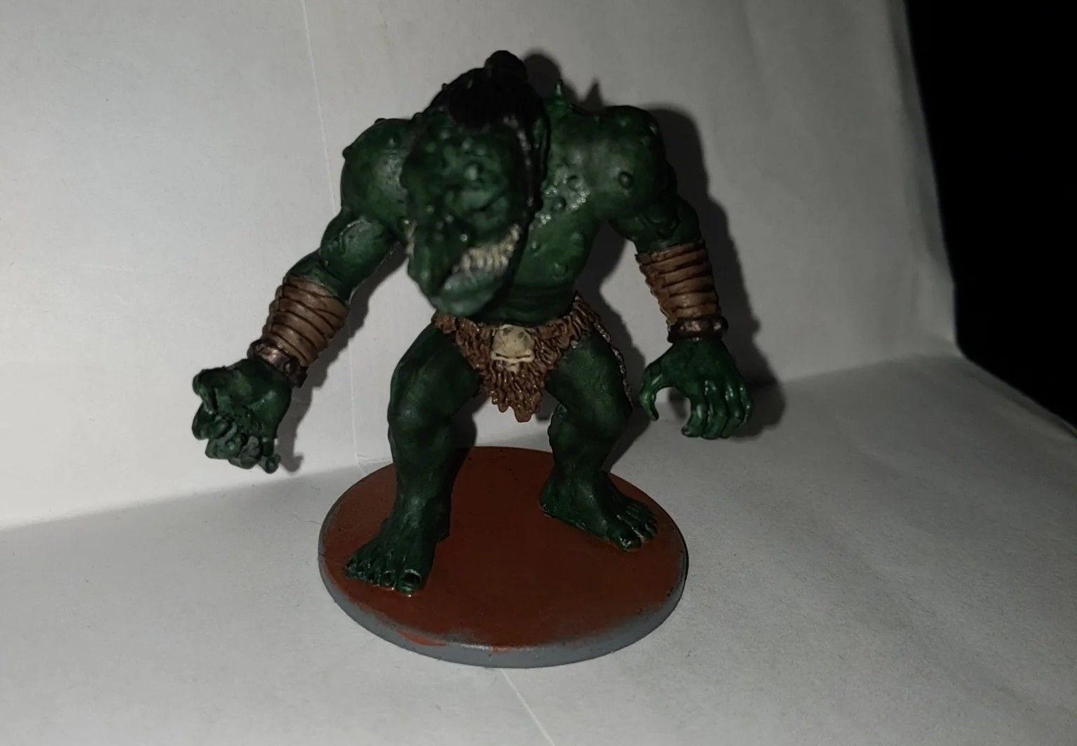 Green troll miniature with brown base, stands menacingly.