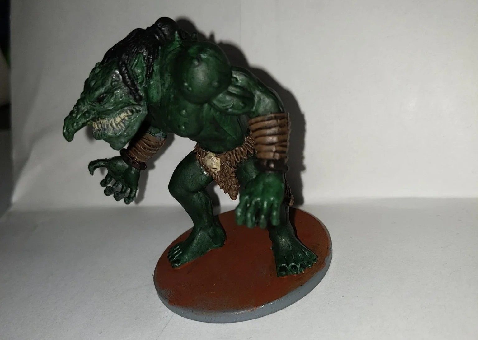 Green-skinned troll miniature with sharp teeth, standing on a brown base.